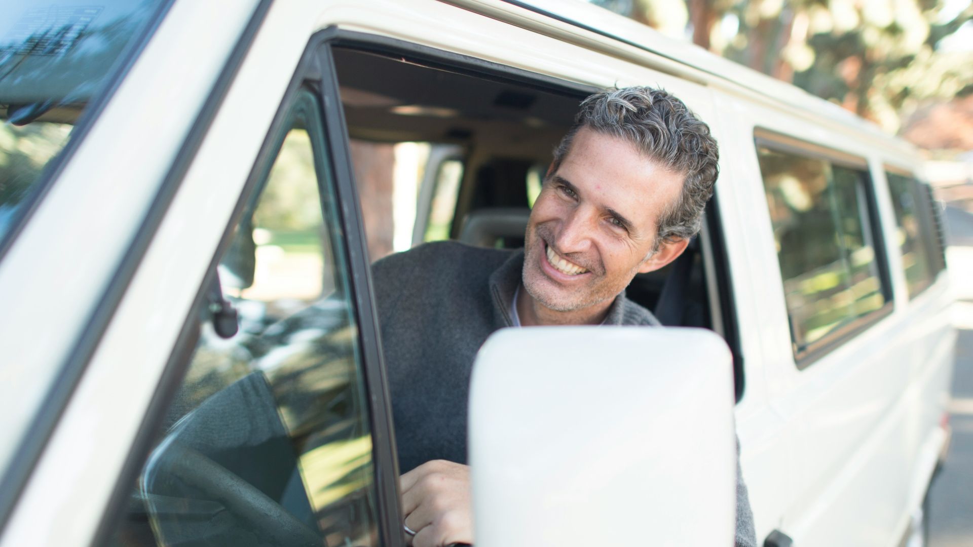 man in gray sweater leaning on van window