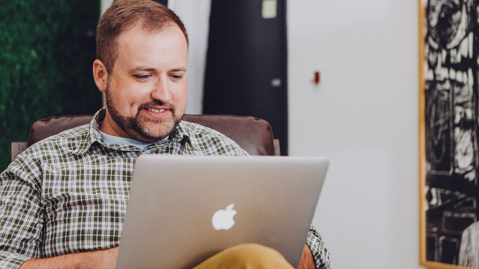 man smiling and using MacBook