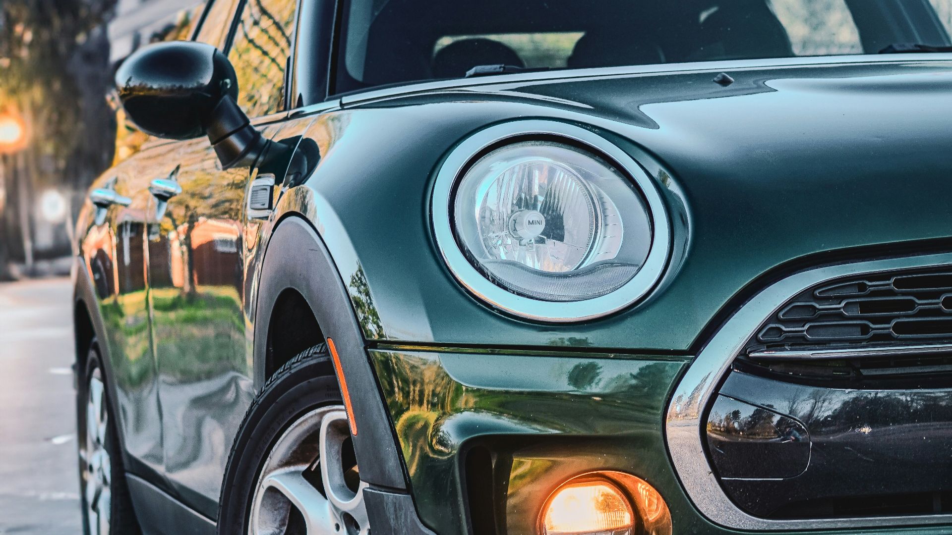 a green mini cooper parked on the side of the road