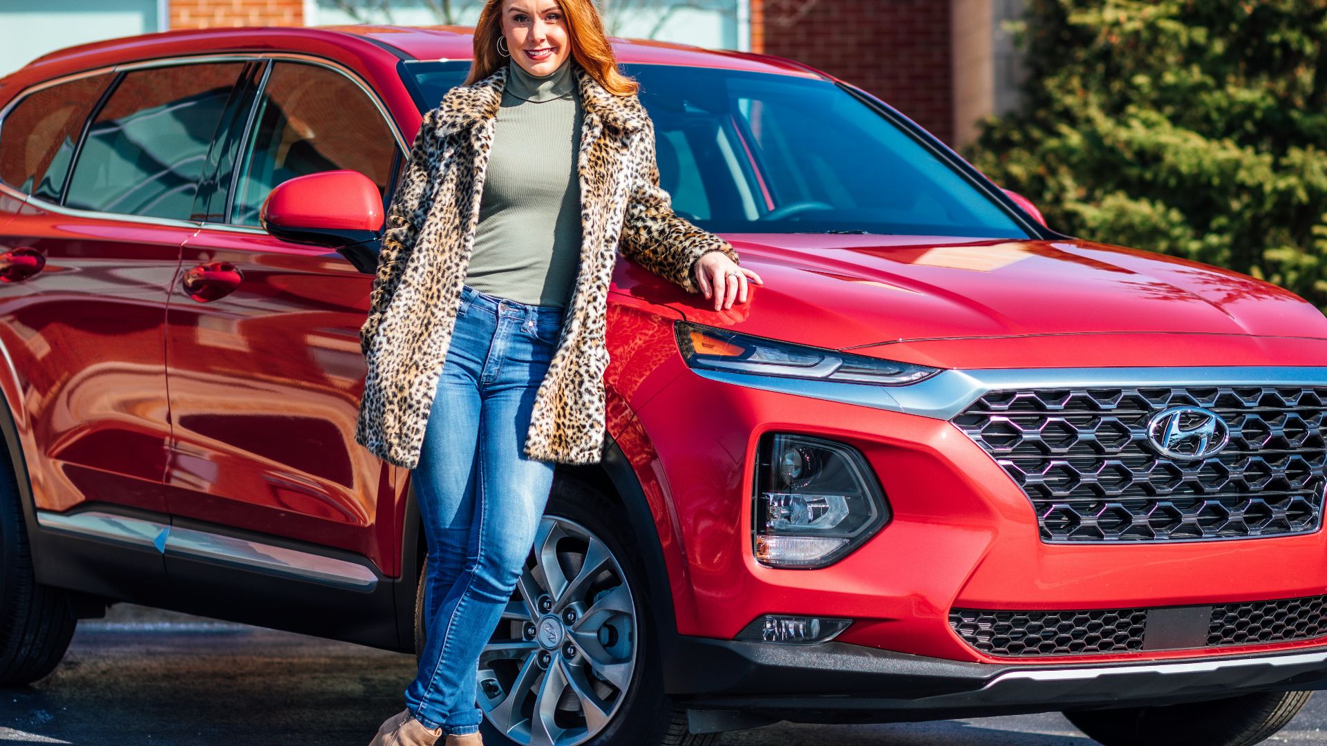 woman in white and black scarf and blue denim jeans standing beside red mercedes benz car
