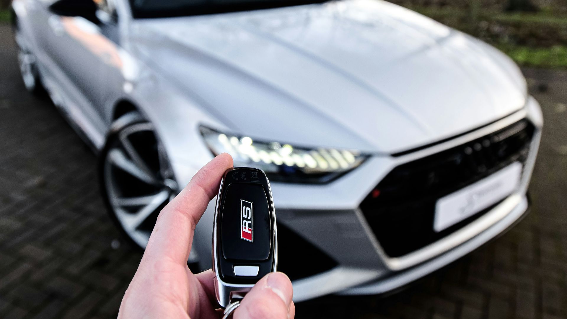 a person holding a car key in front of a silver car