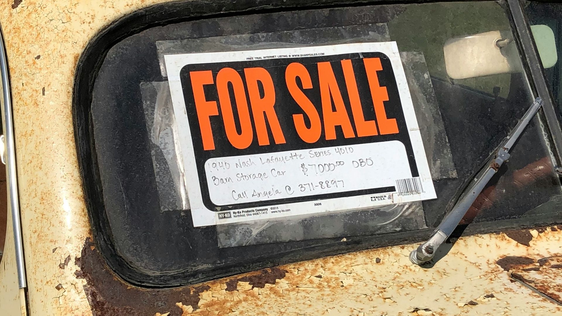 a rusted out car with a for sale sign on it