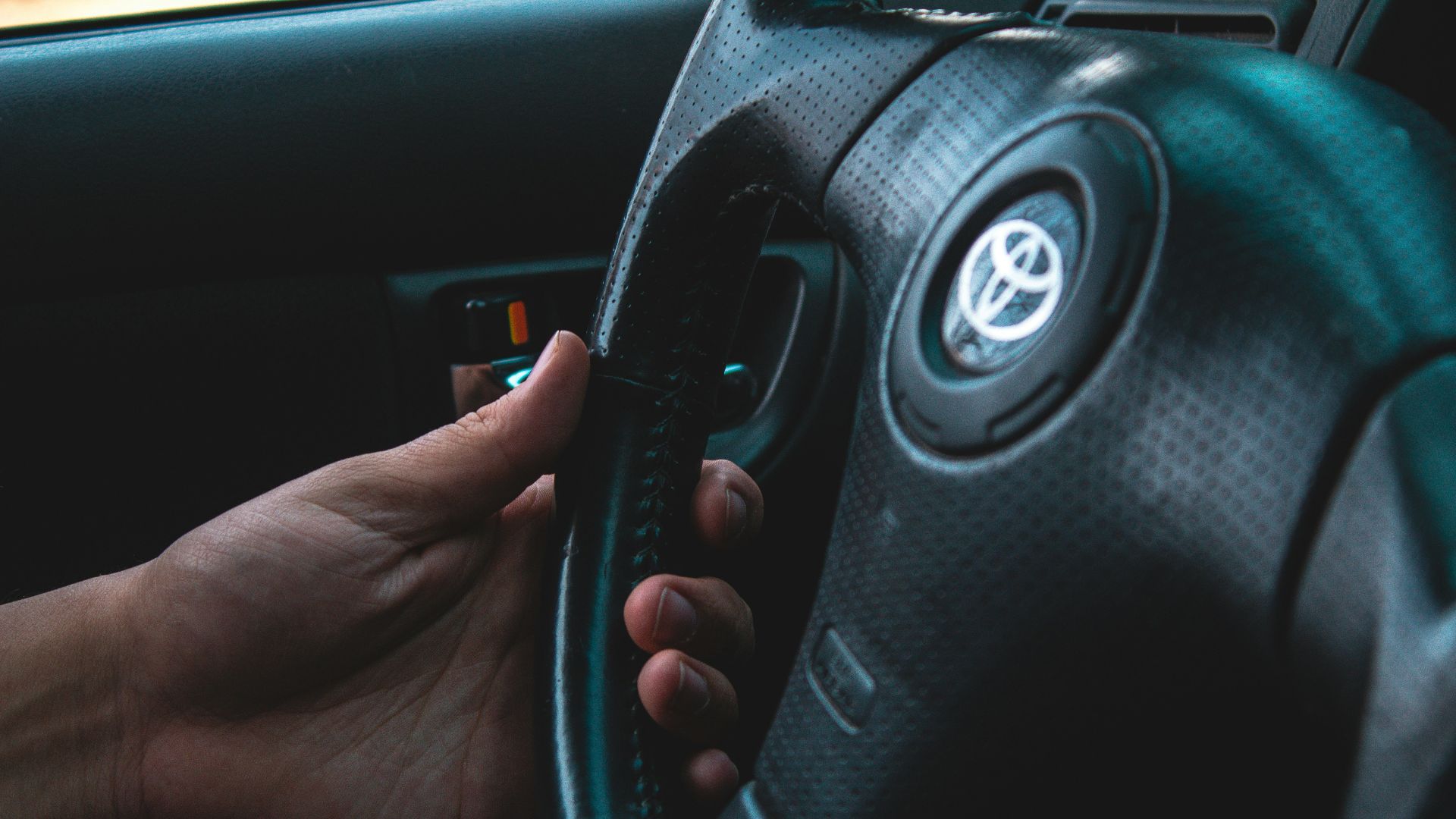 person holding black Toyota vehicle steering wheel