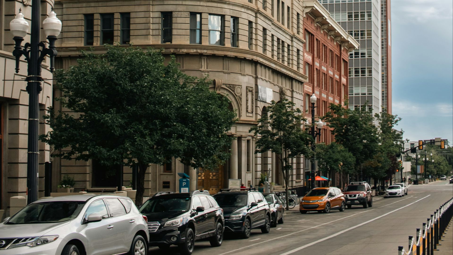 A city street lined with tall buildings and parked cars