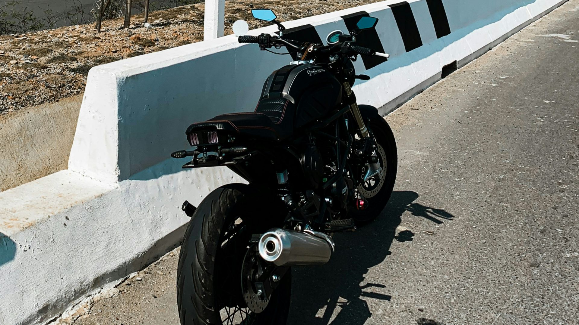 black motorcycle parked on gray concrete road during daytime