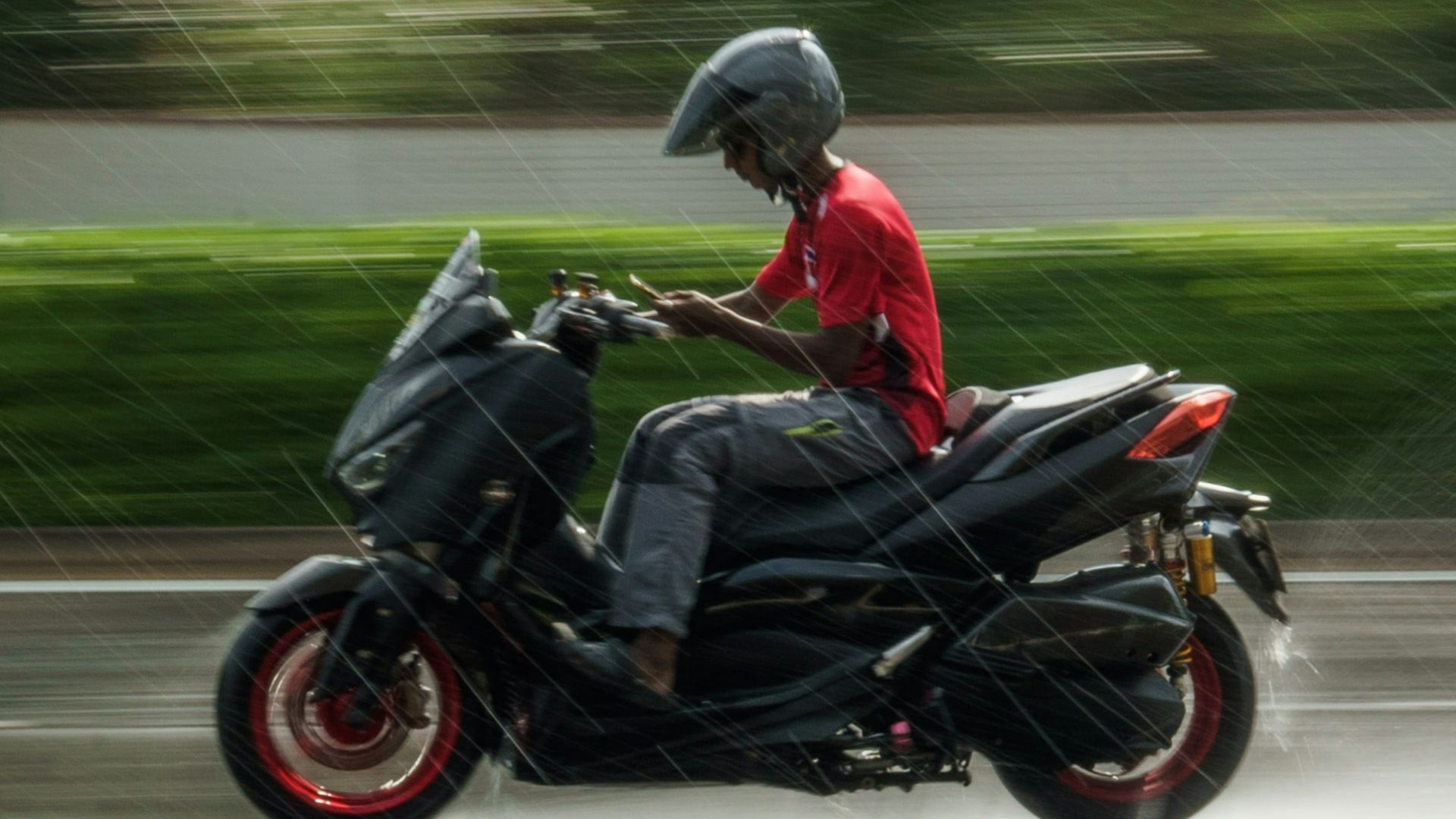 a man riding a motorcycle down a rain soaked street