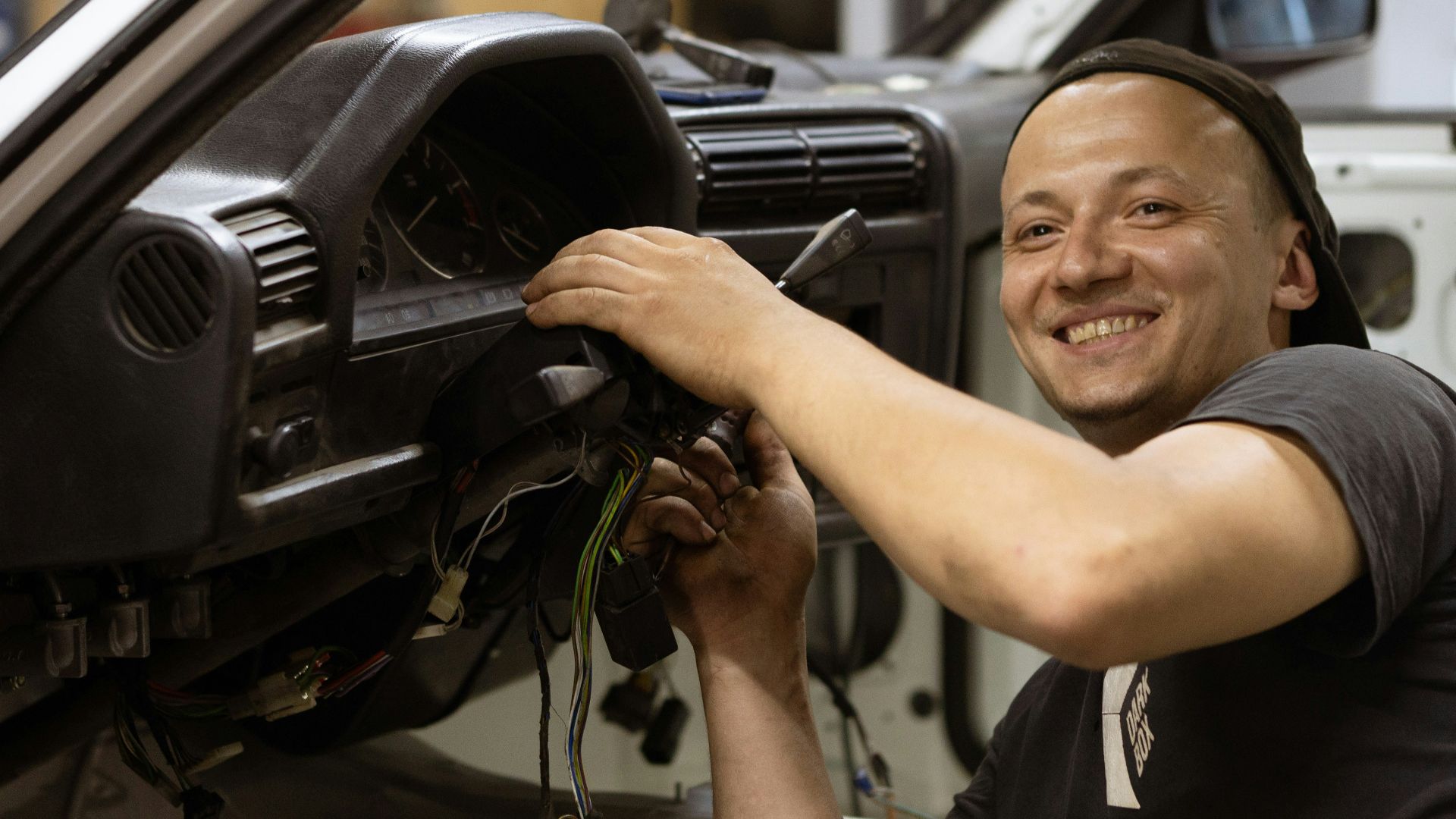 man in black crew neck t-shirt holding black car steering wheel