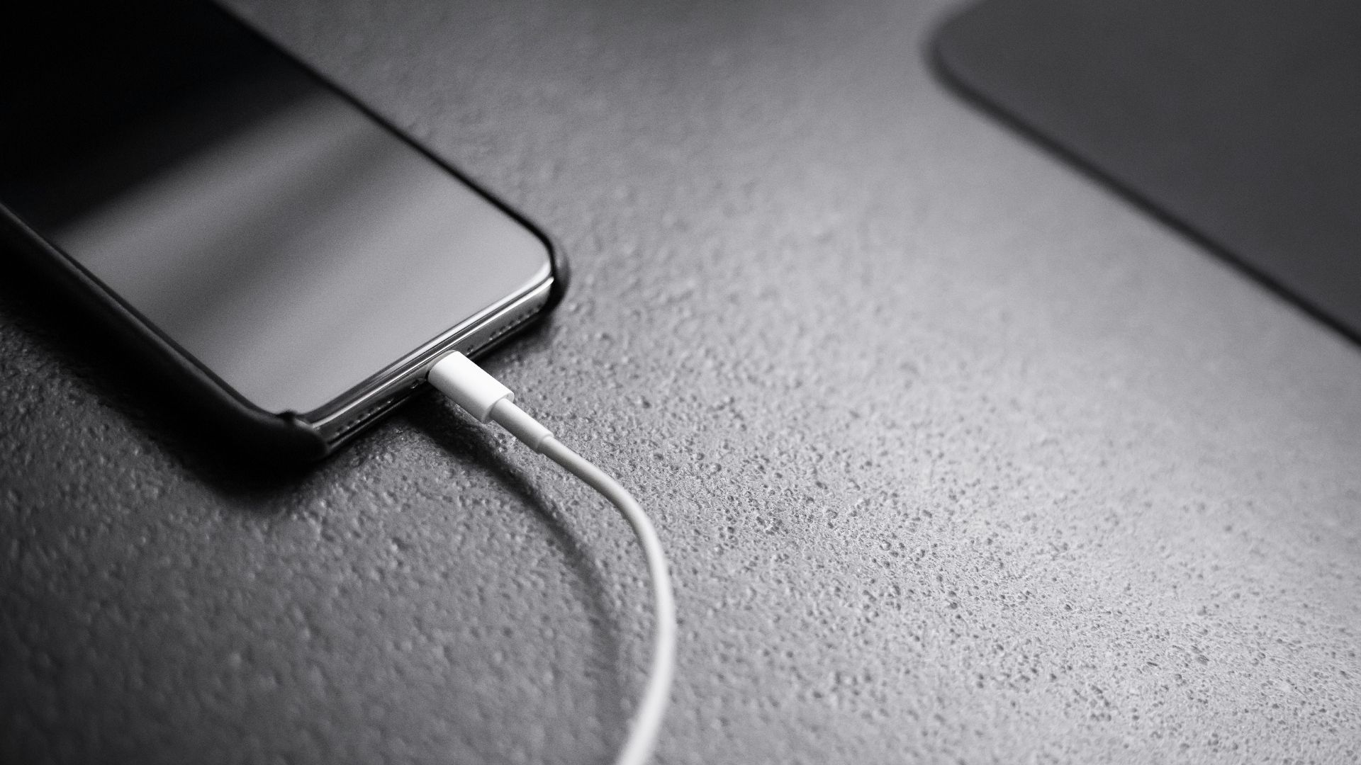 black smartphone with charger cord connected