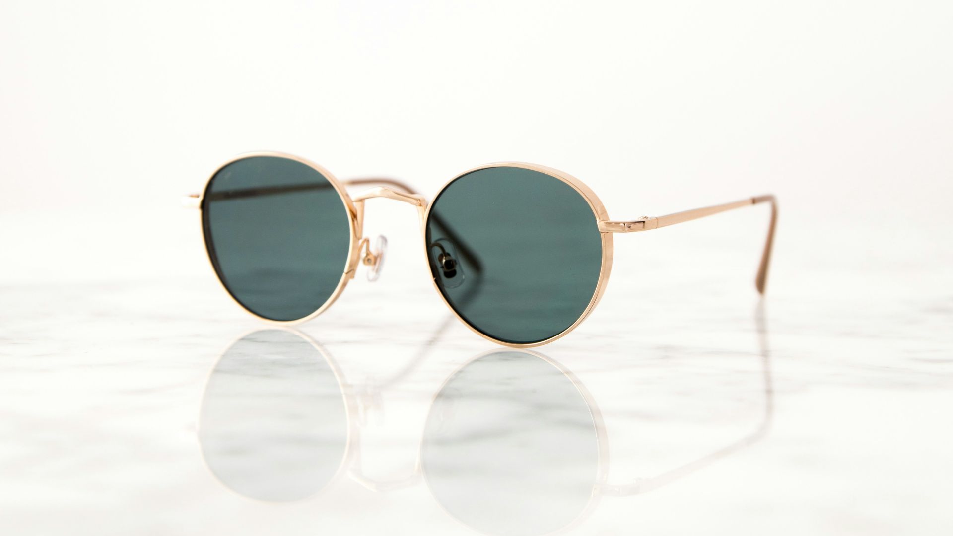 gold-colored framed hippie sunglasses on white surface