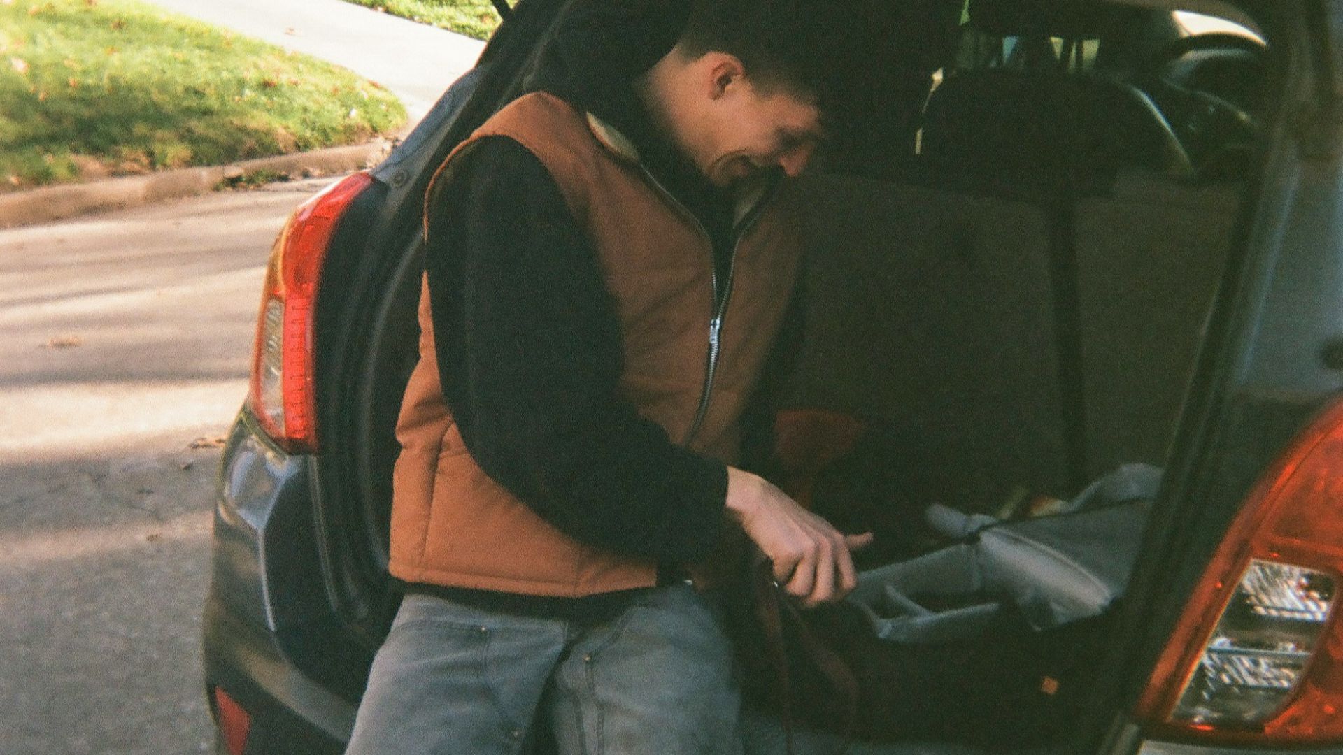 man in black jacket sitting on black car