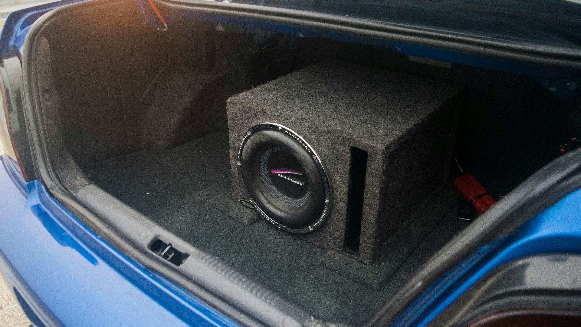 A car trunk contains a subwoofer system.