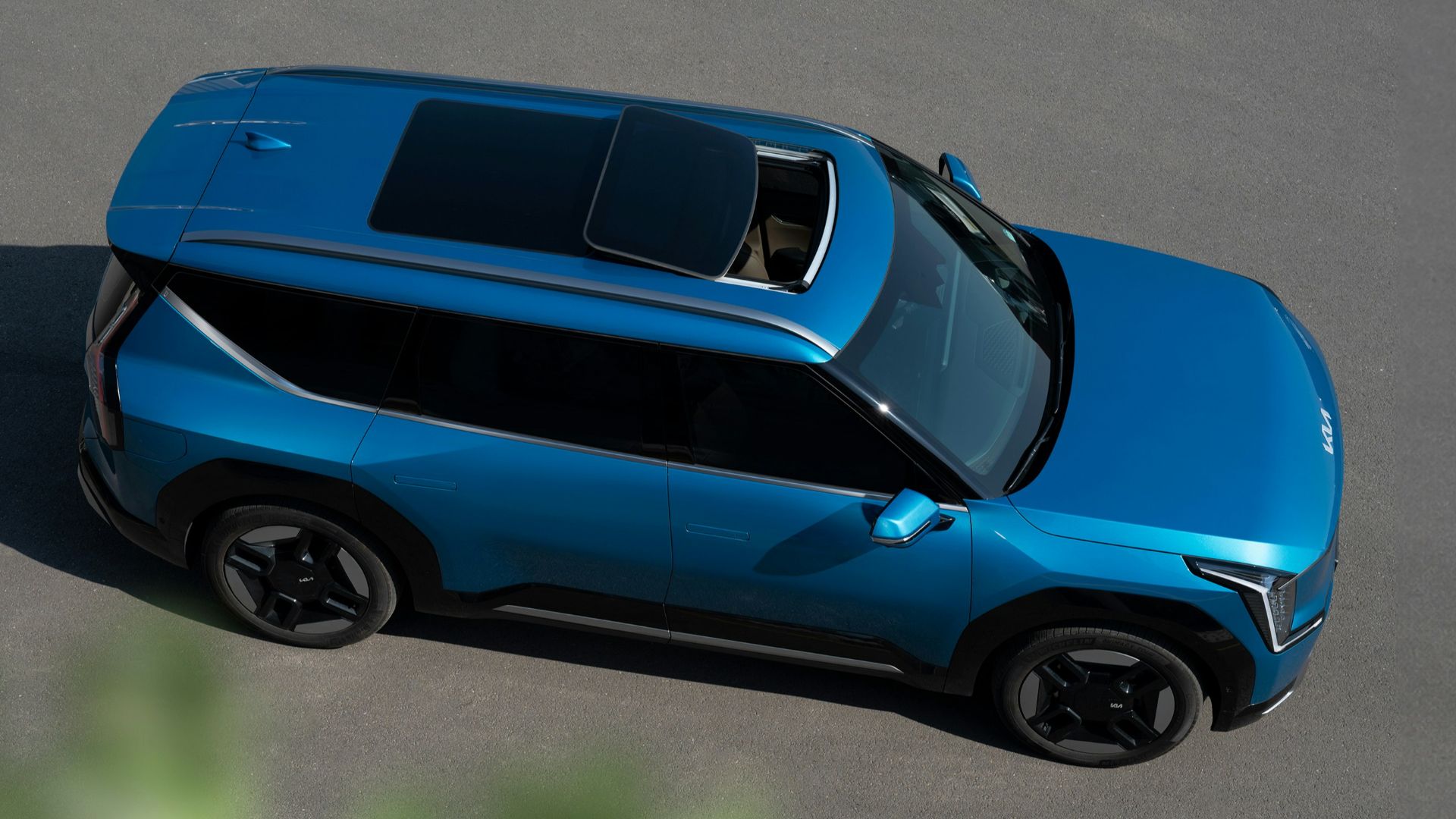 a blue car driving down a road next to a forest