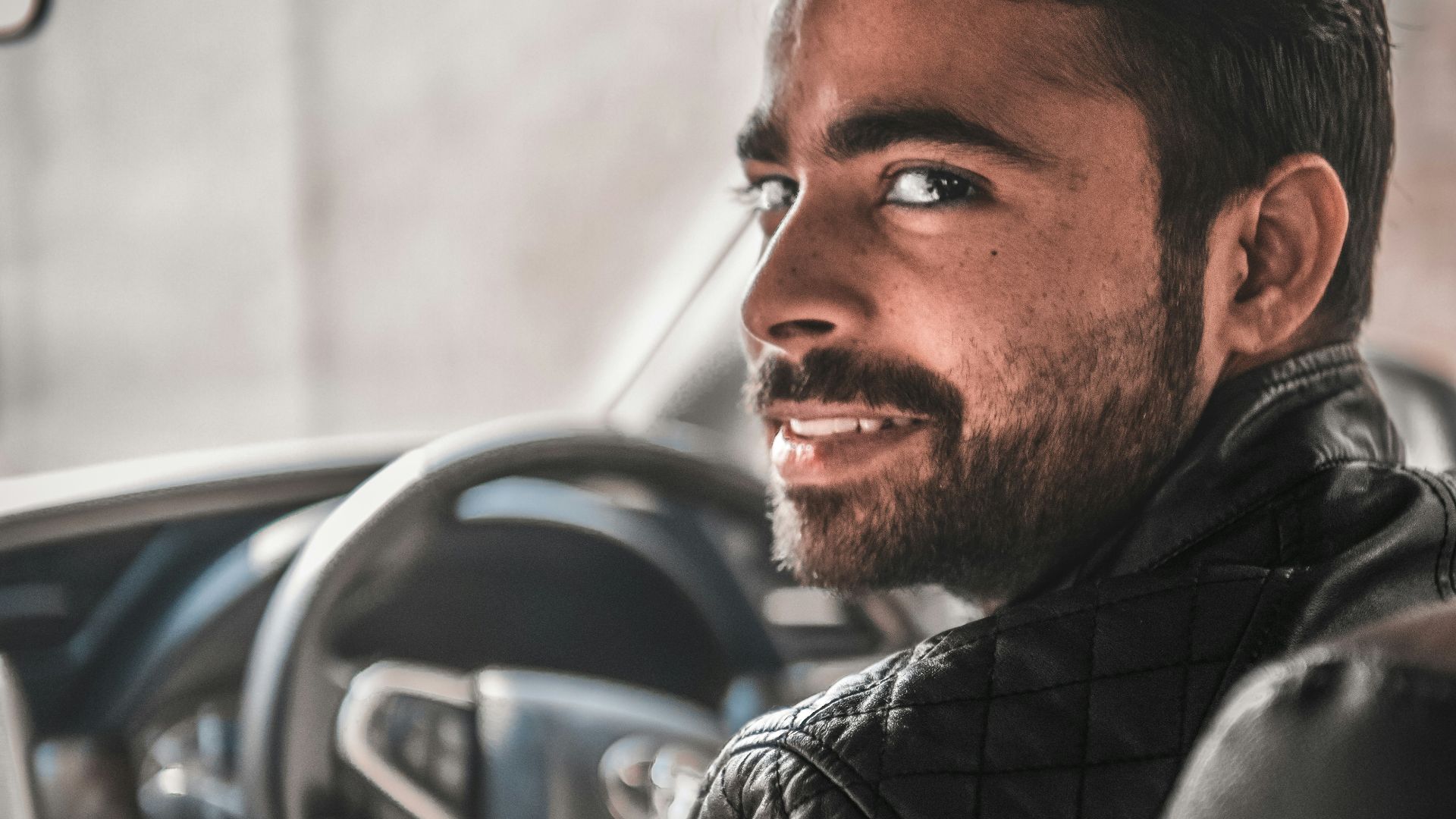man in black leather jacket sitting on blue car seat
