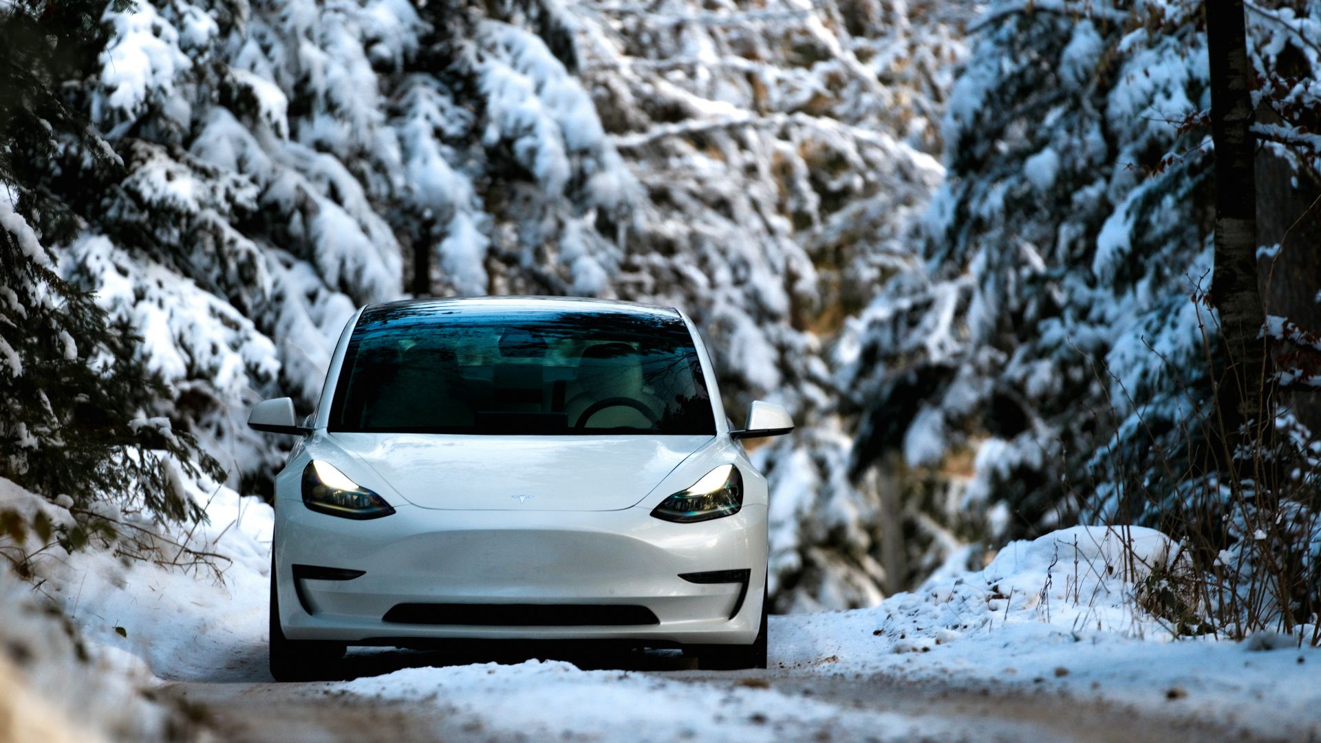 a white car driving down a snow covered road