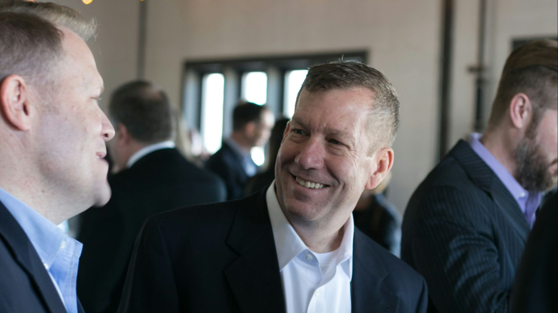 man in black suit jacket smiling
