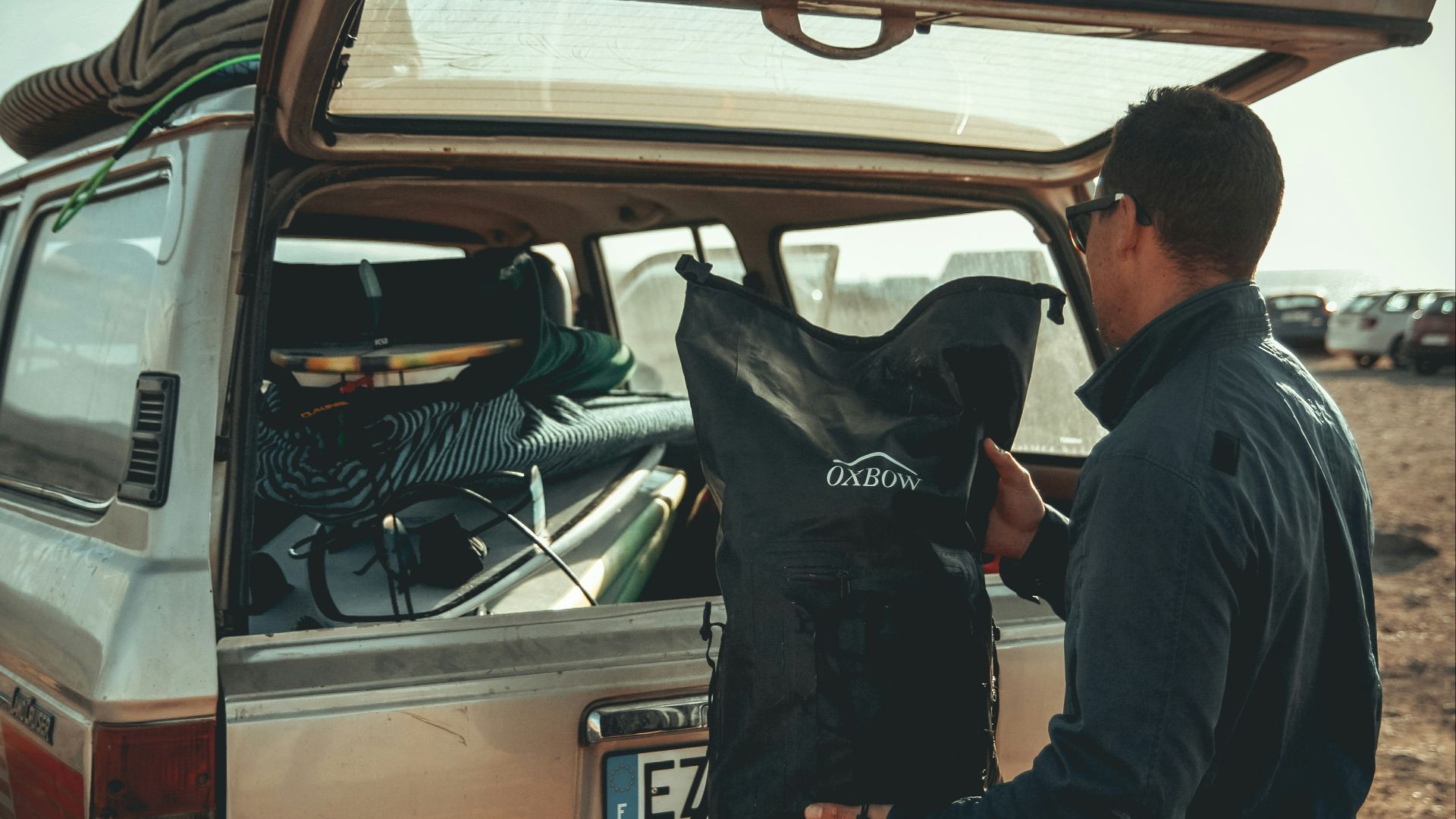 man loading black bag in back of suv