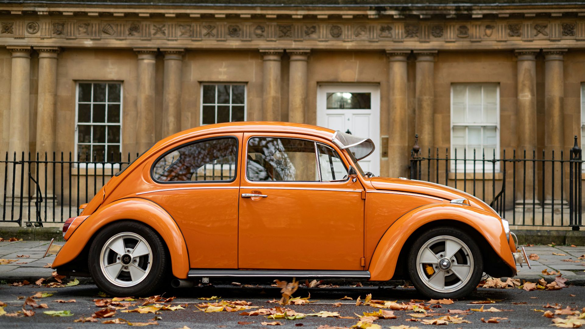 orange volkswagen beetle parked near building