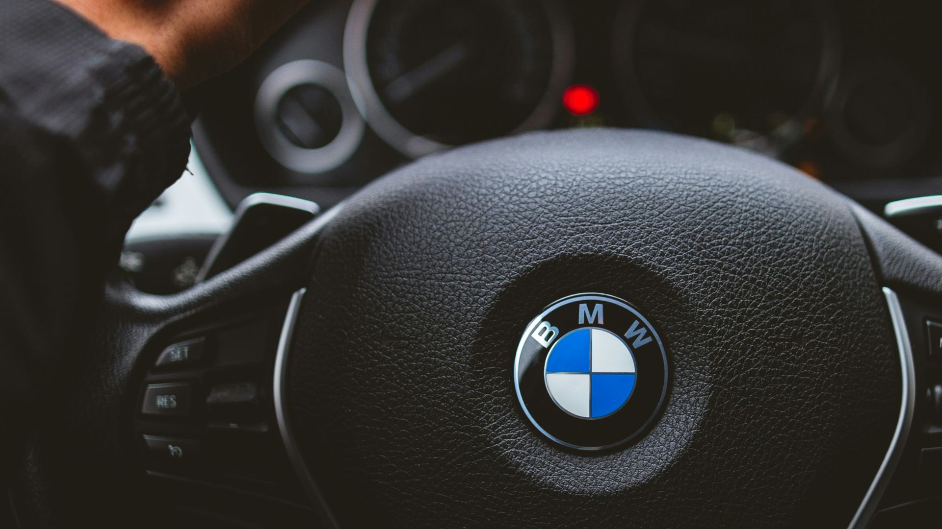person holding BMW vehicle steering wheel