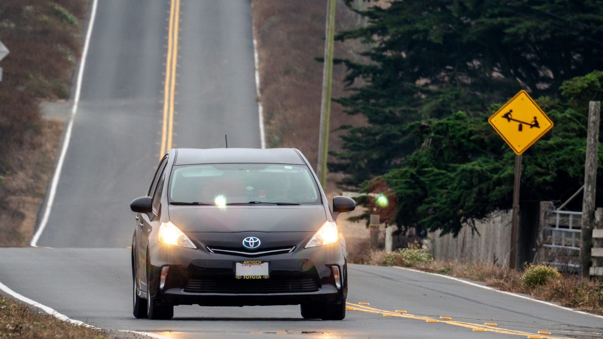 a car driving down a road next to a hill