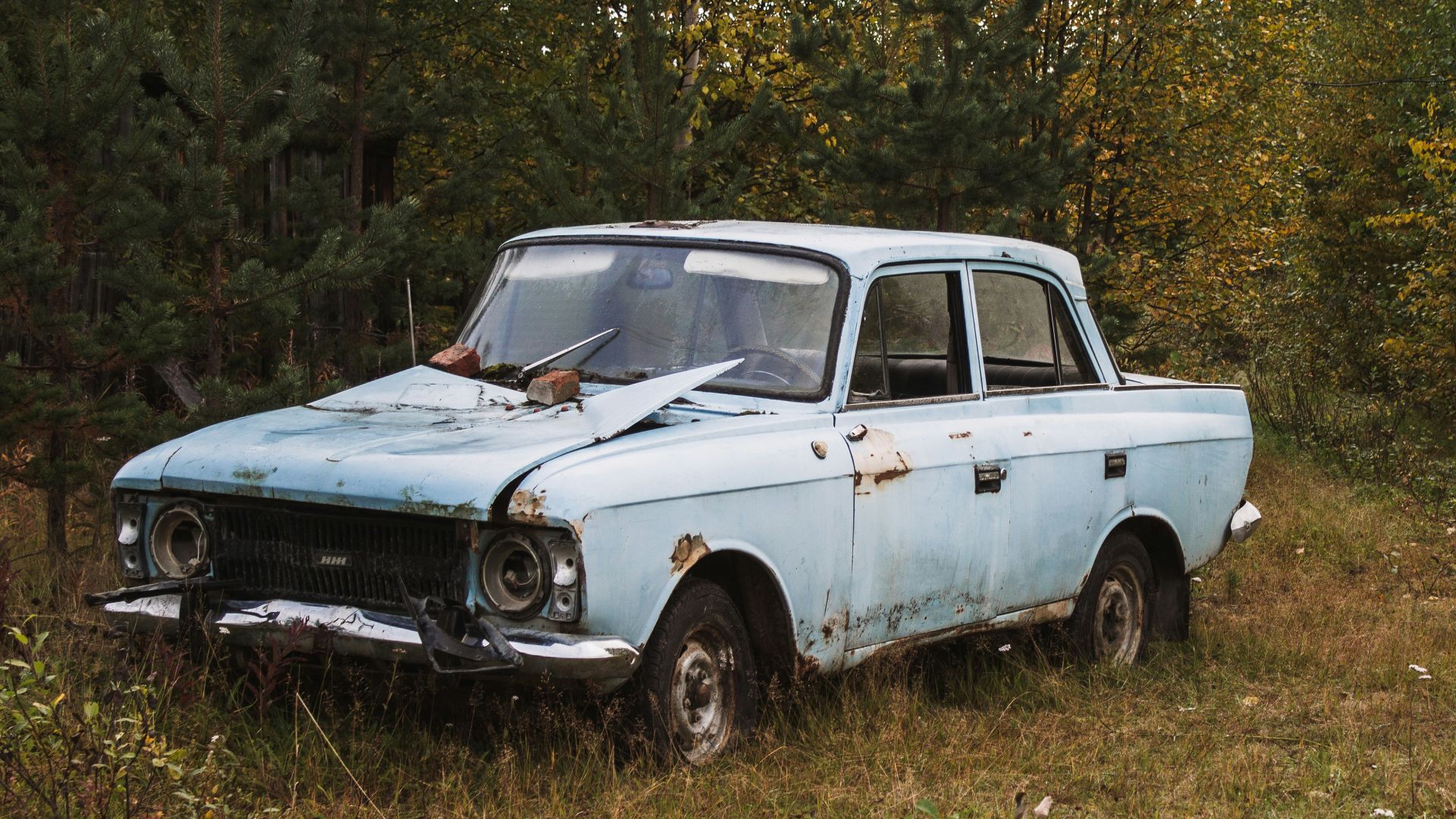 an old blue car is parked in a field