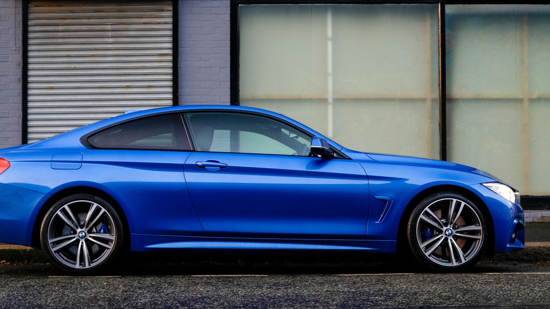 blue coupe beside gray house