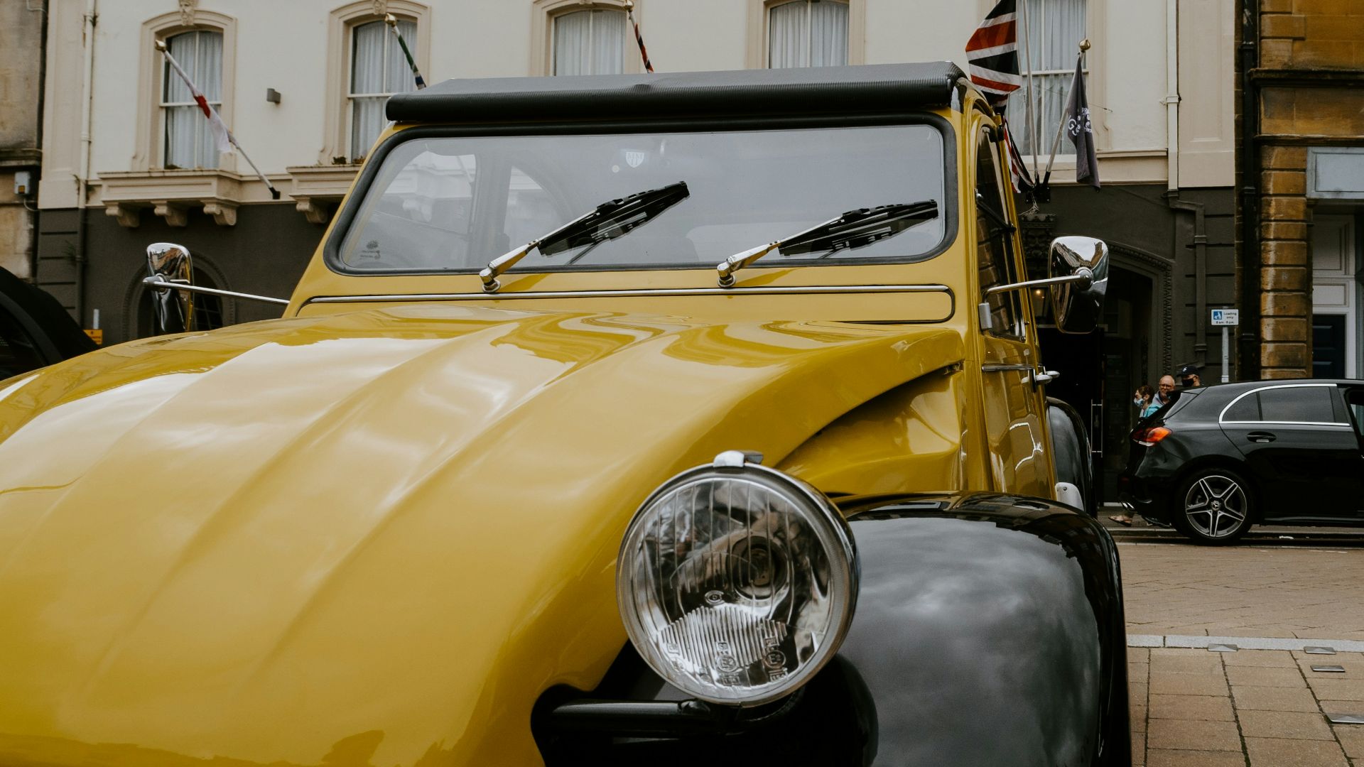 yellow and black vintage car parked beside white concrete building during daytime