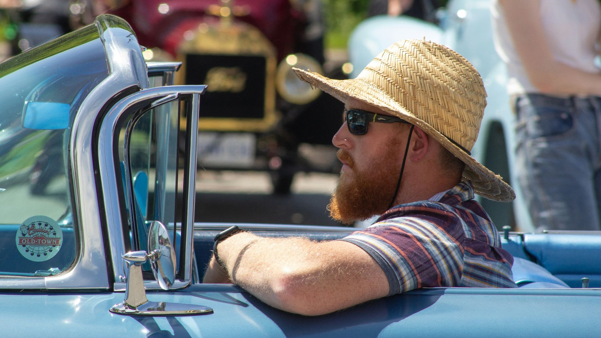 A man in a straw hat sitting in the back of a blue truck