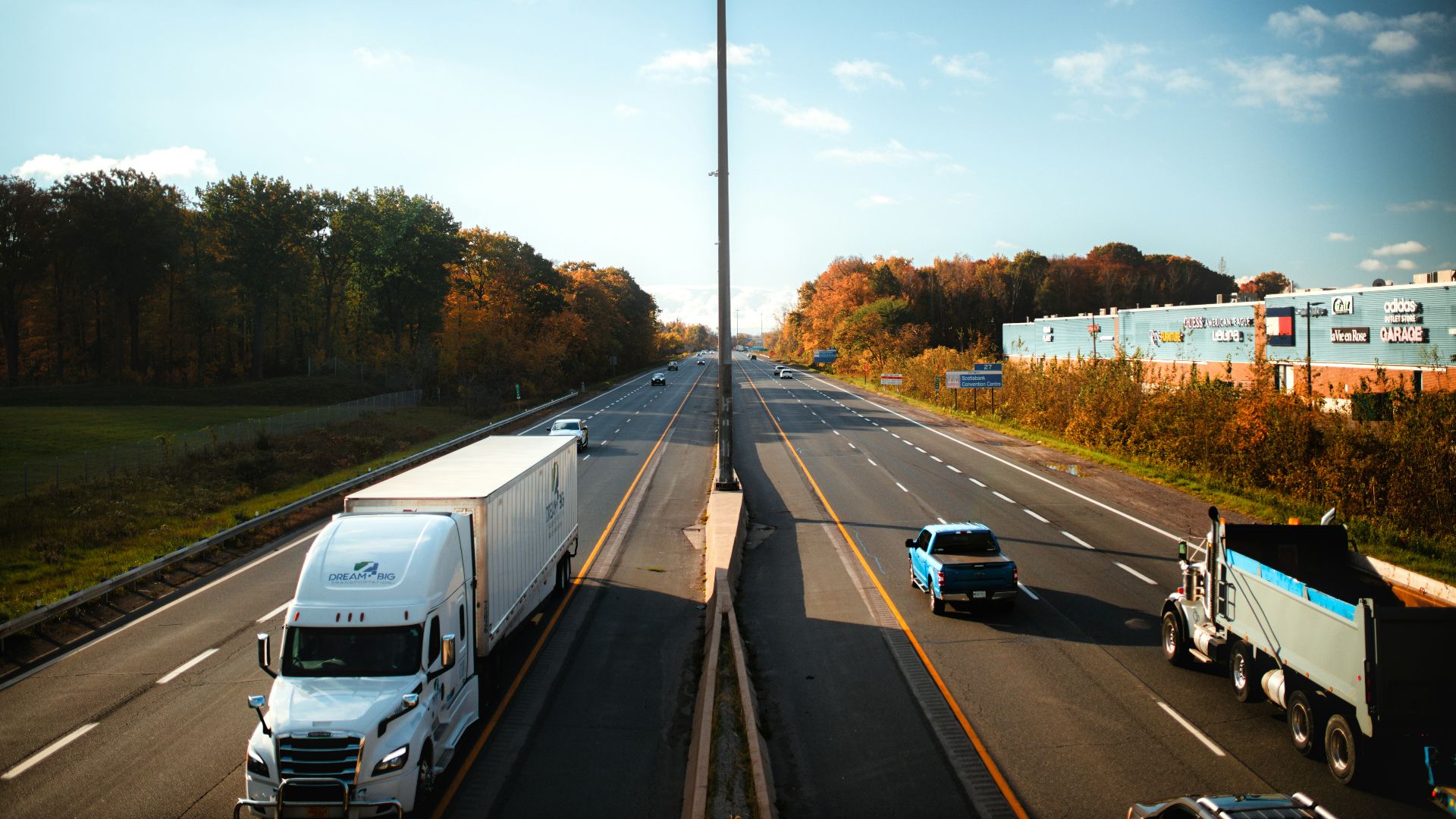 a highway filled with lots of traffic next to a forest
