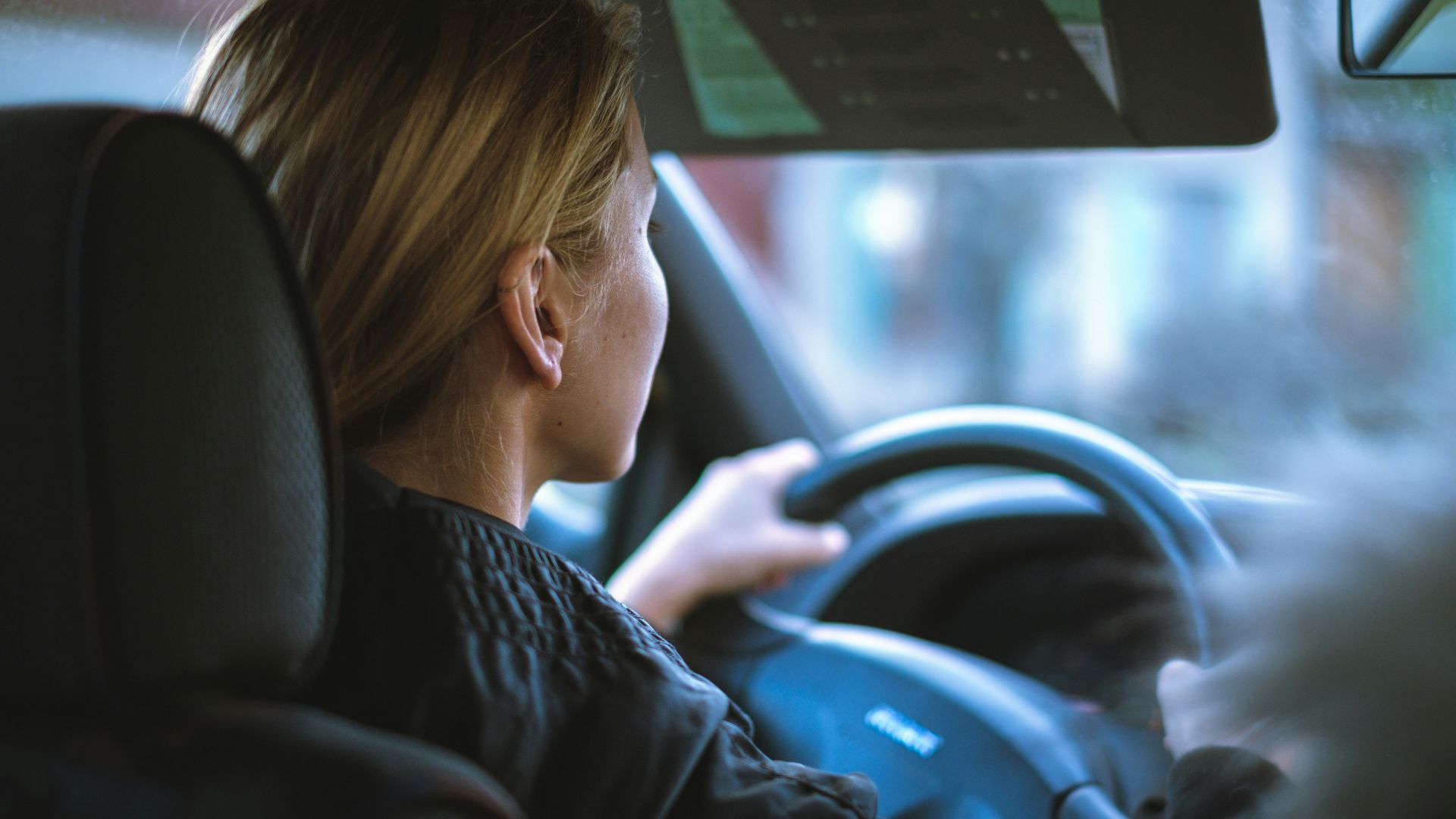 a woman sitting in a car with a steering wheel