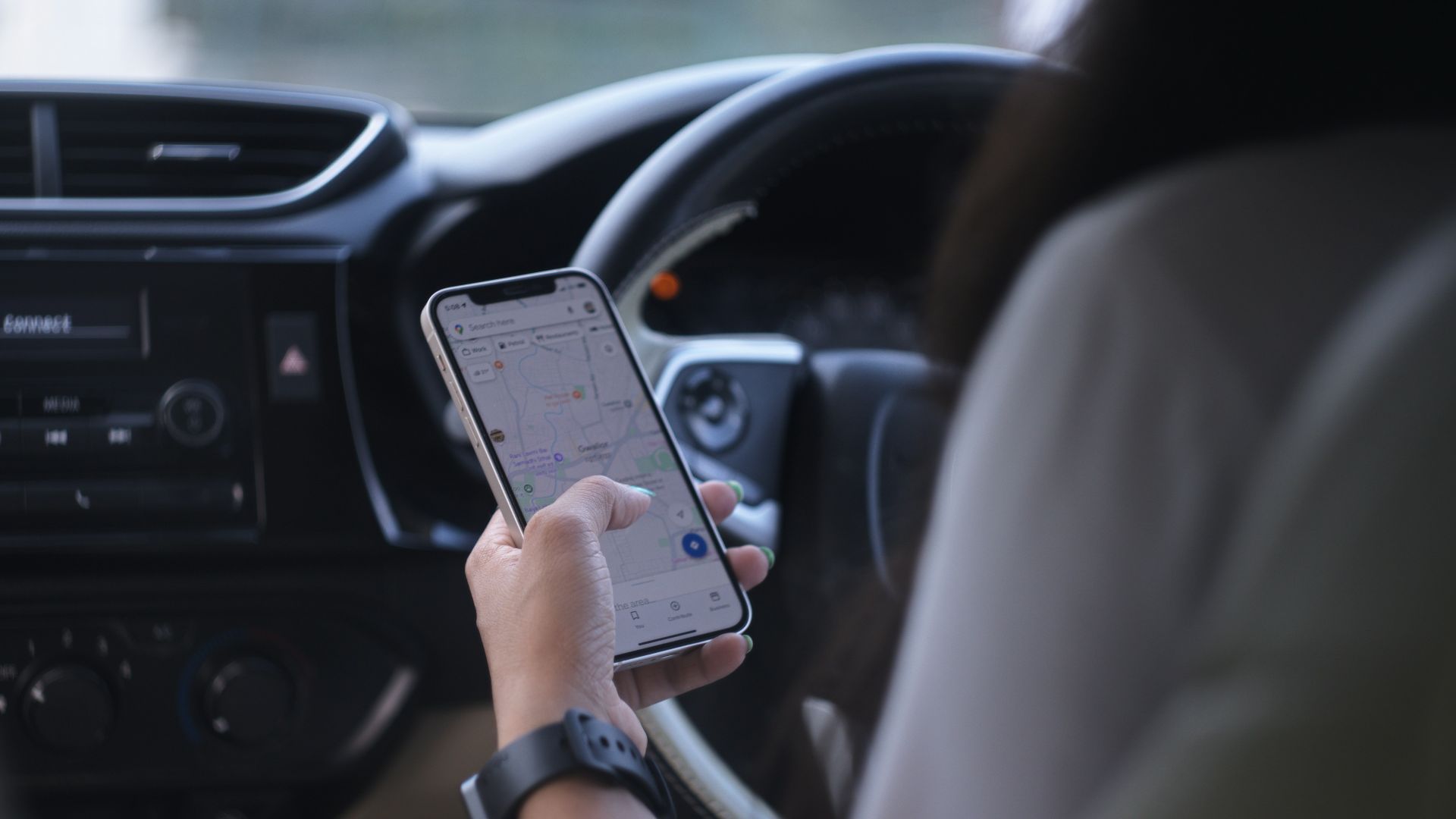 A woman holding a cell phone while driving a car