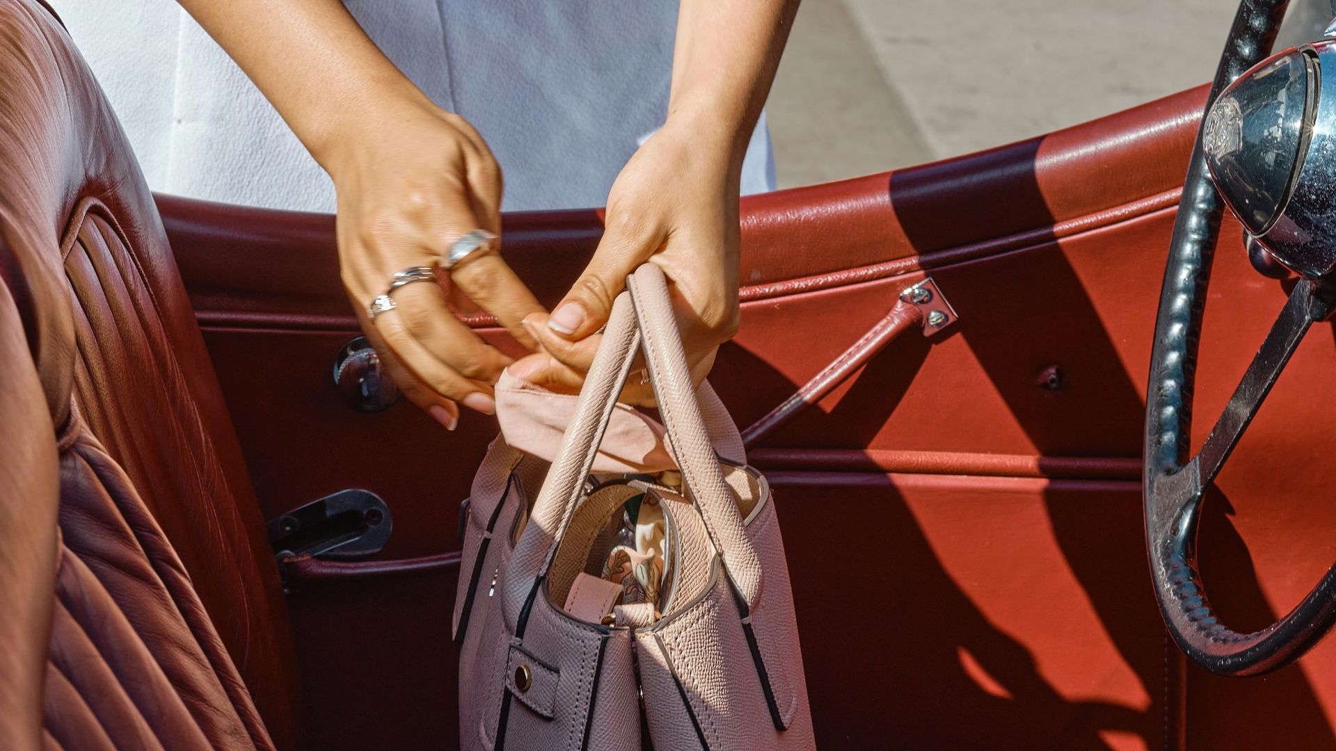 gray leather handbag on brown leather car seat