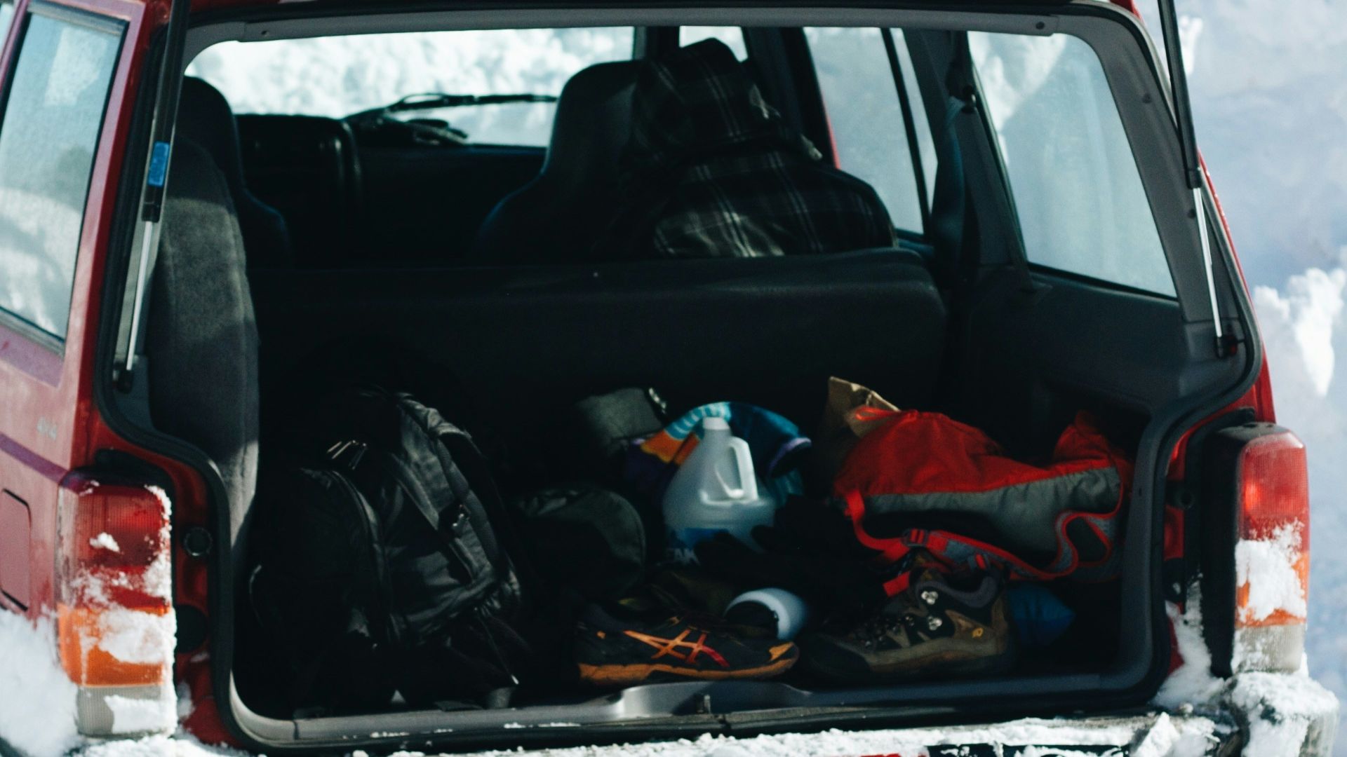 red and black car on snow covered ground during daytime