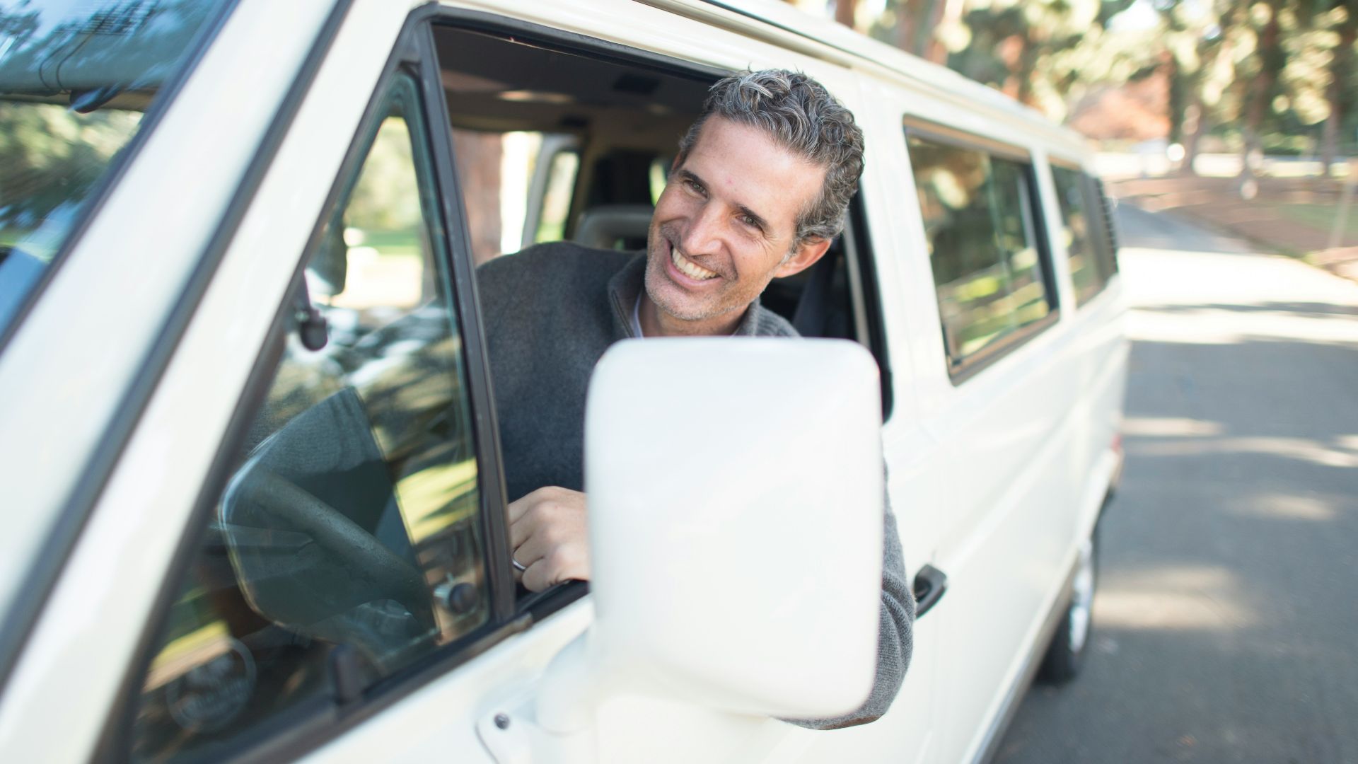 man in gray sweater leaning on van window