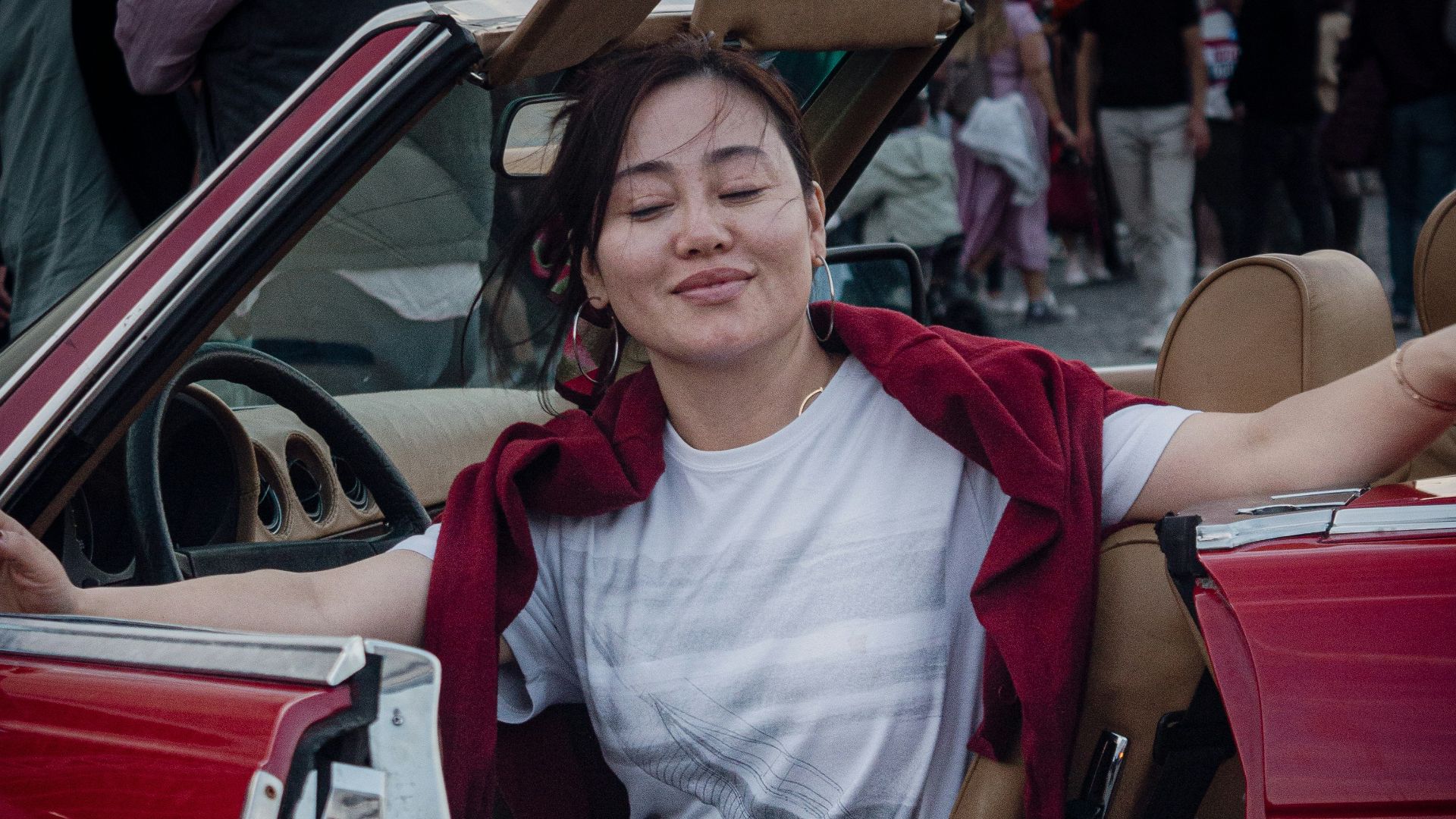 a woman sitting in the driver's seat of a red car
