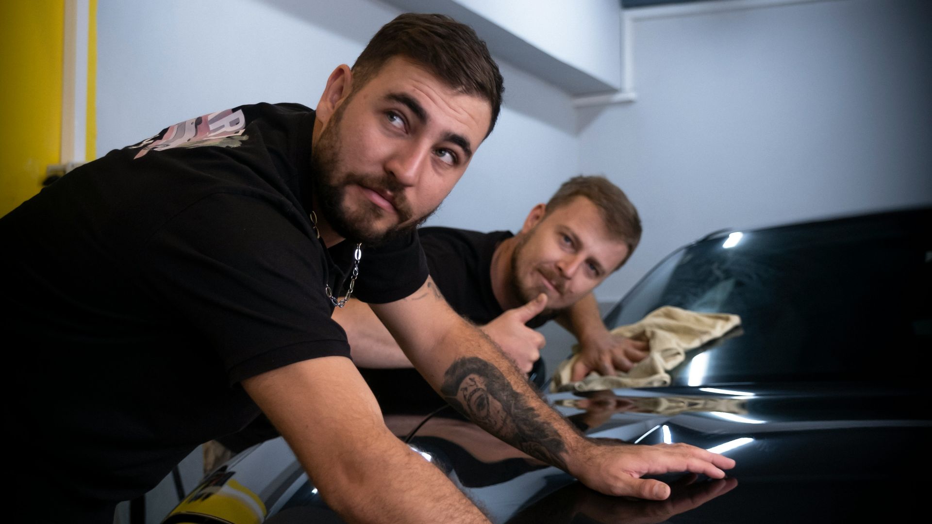two men waxing a car in a garage