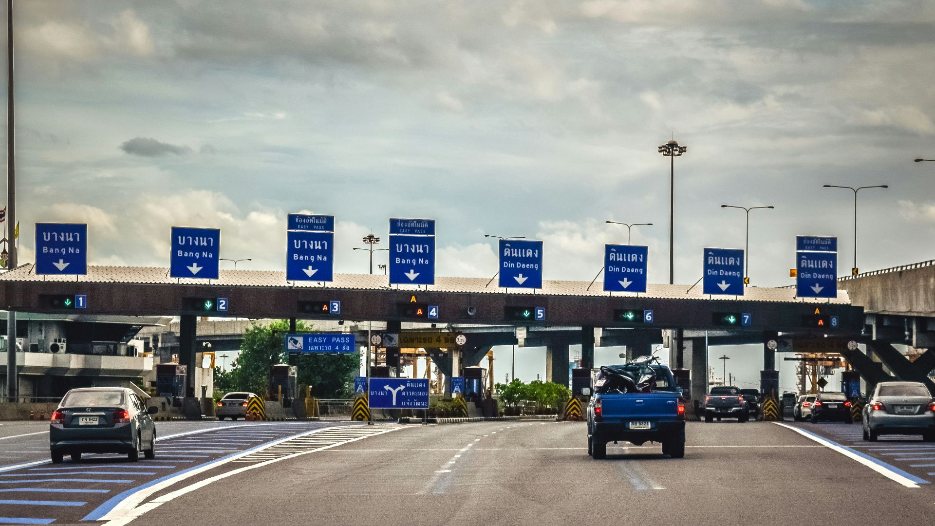 A blue truck driving down a highway under a cloudy sky