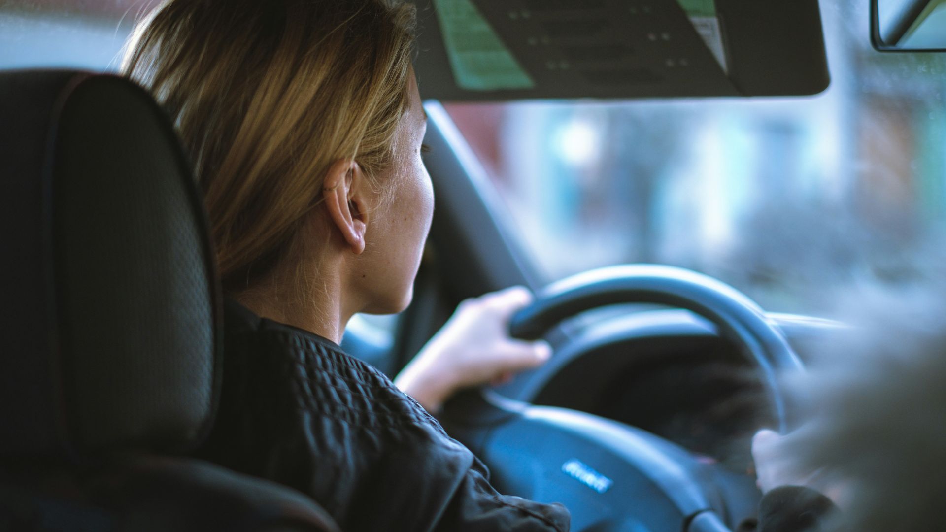a woman sitting in a car with a steering wheel