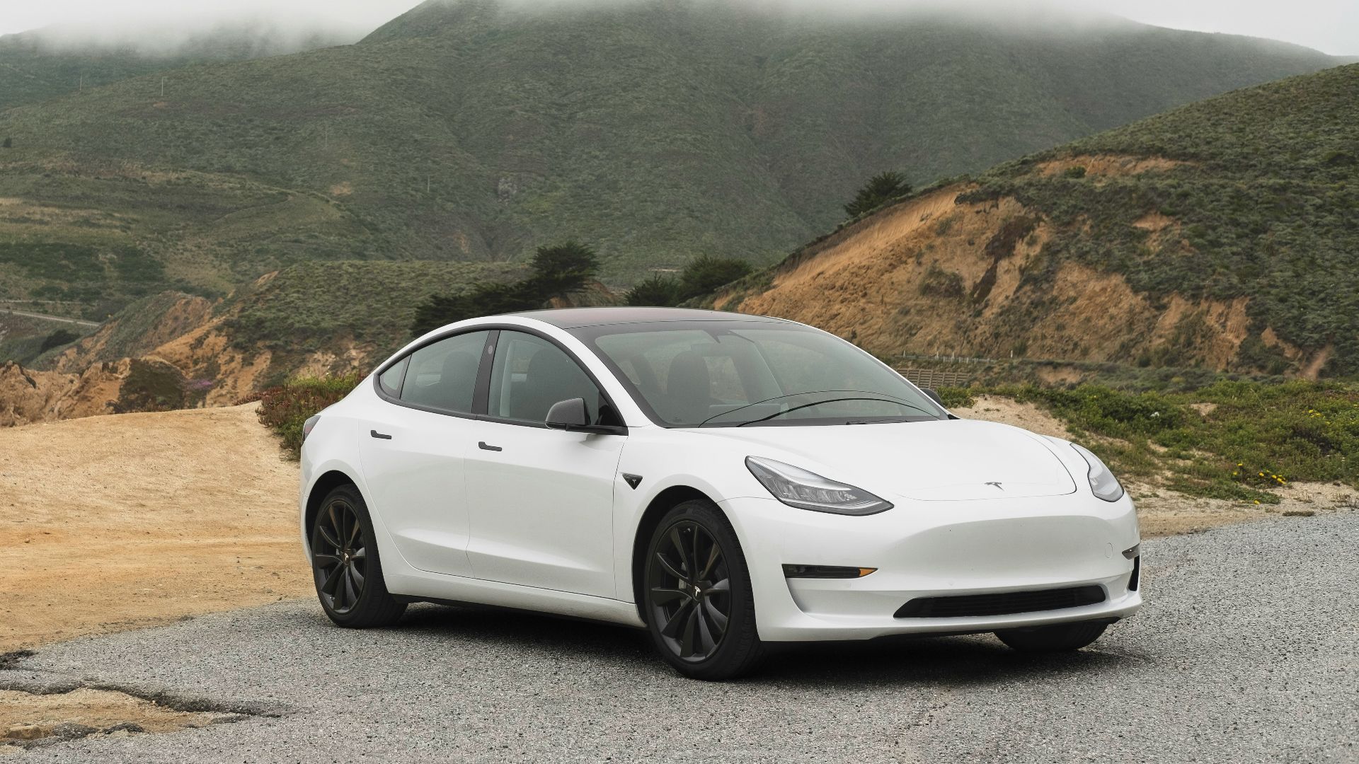 white sedan parked beside mountain during daytime