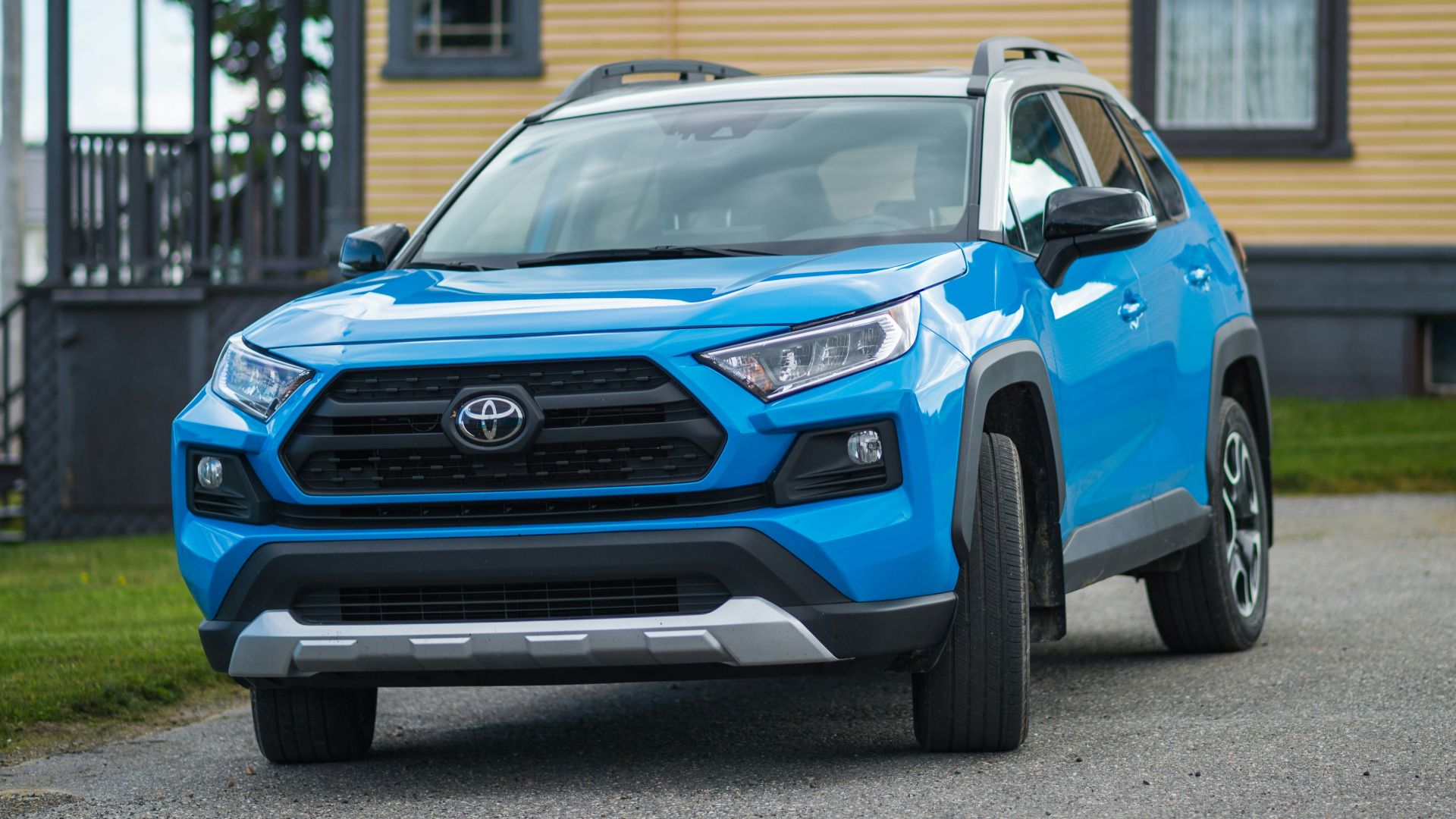 a blue toyota rav parked in front of a house