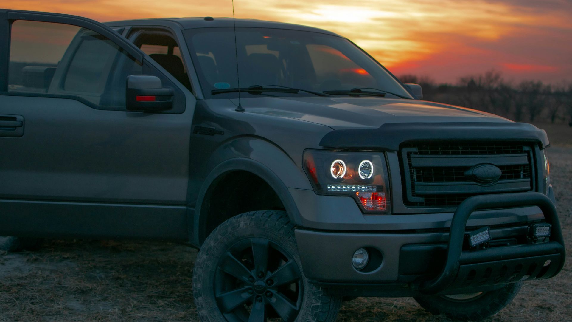 a pickup truck parked in a field at sunset