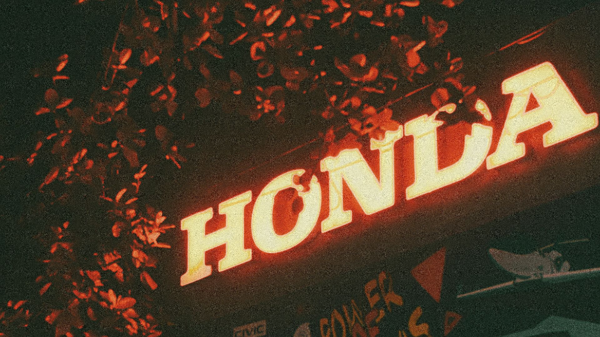 a neon sign that reads honda above a car