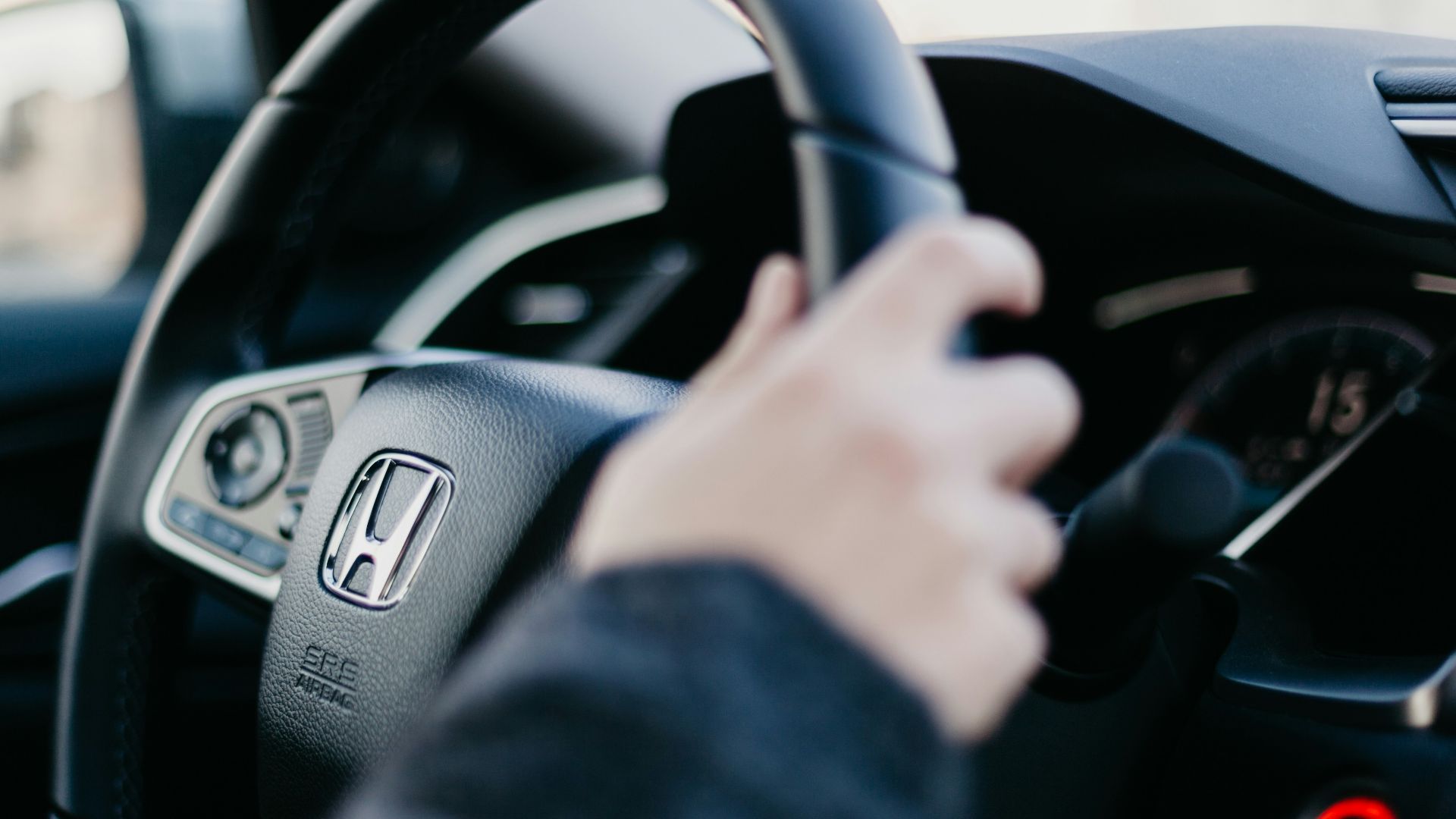 shallow focus photo of person driving Honda car
