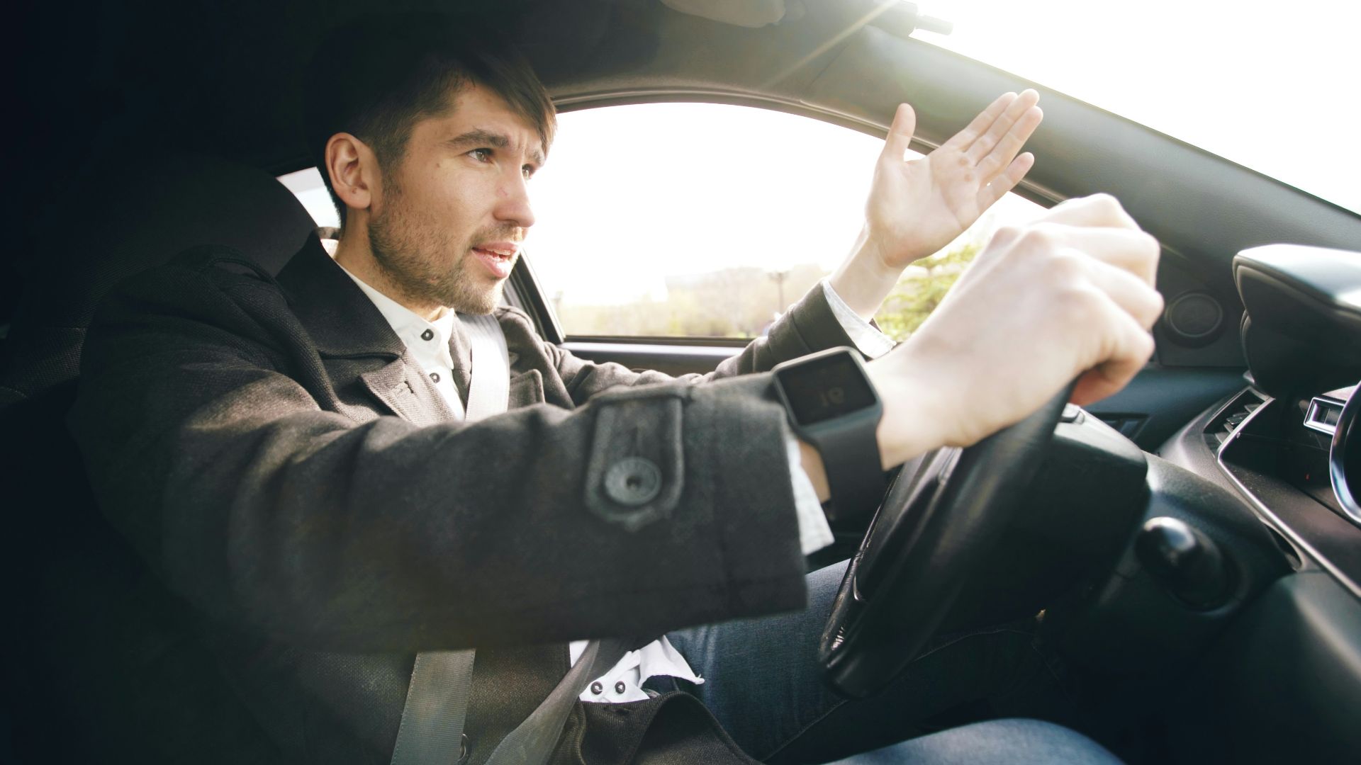 Man driving a car, gesturing with hand.