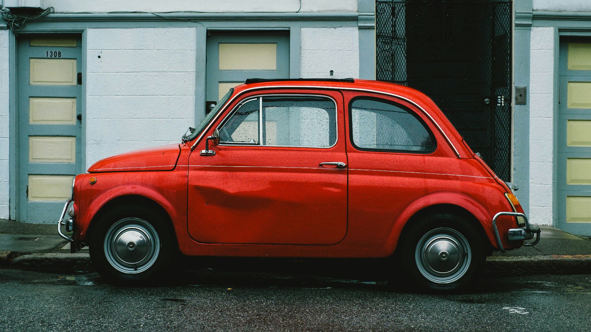 red Volkswagen Beetle car parked in front of white house