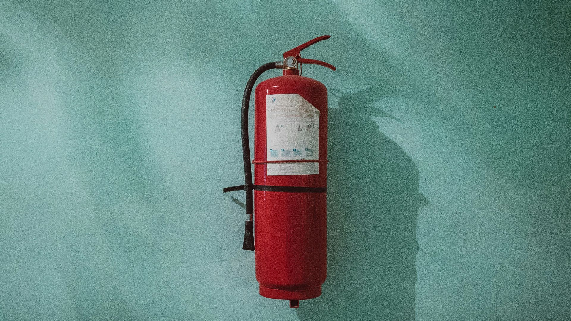 red fire extinguisher on green wall