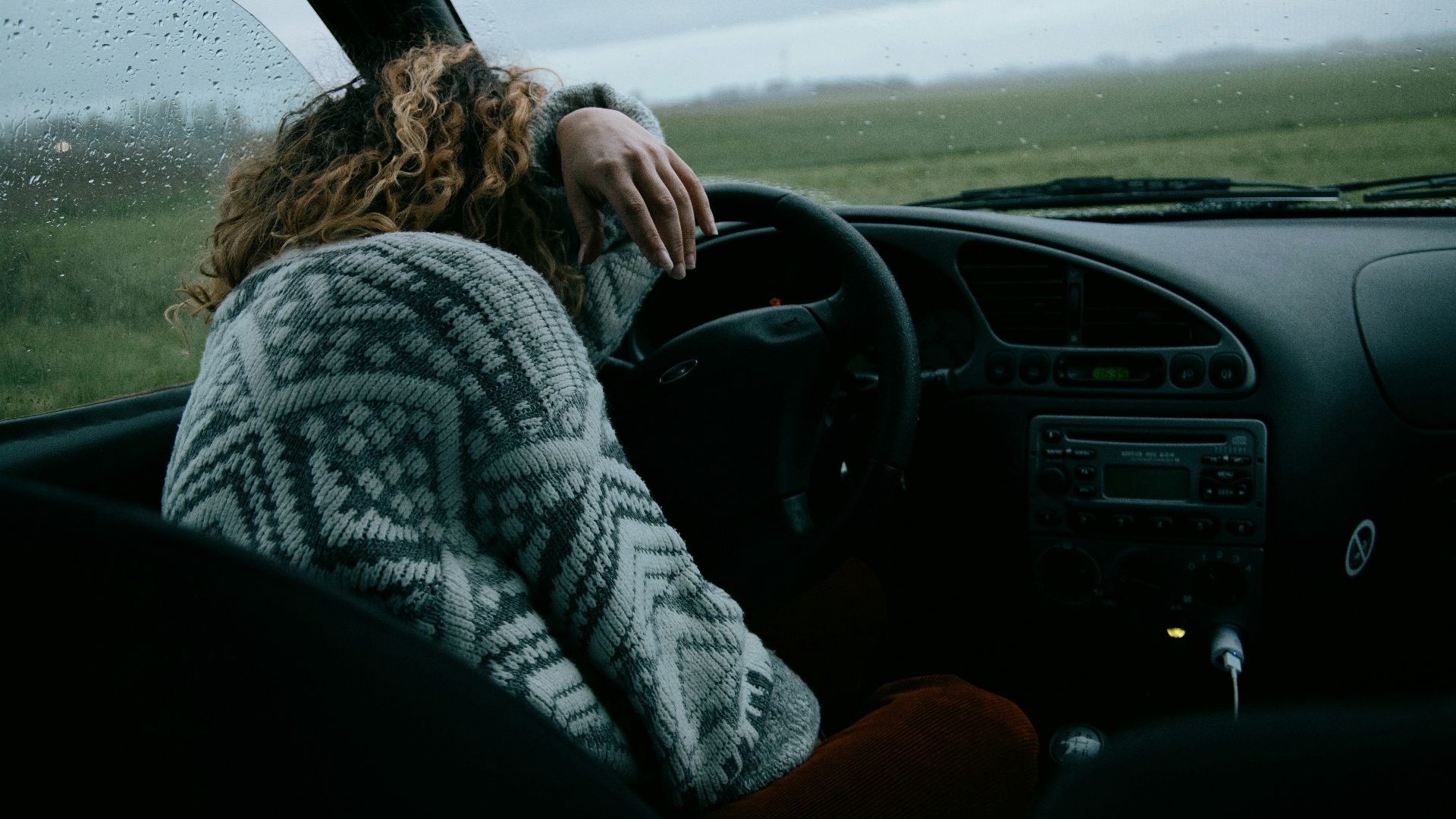 person in gray and white sweater driving car
