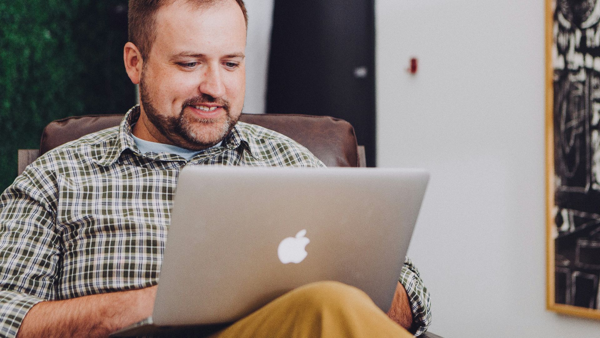 man smiling and using MacBook