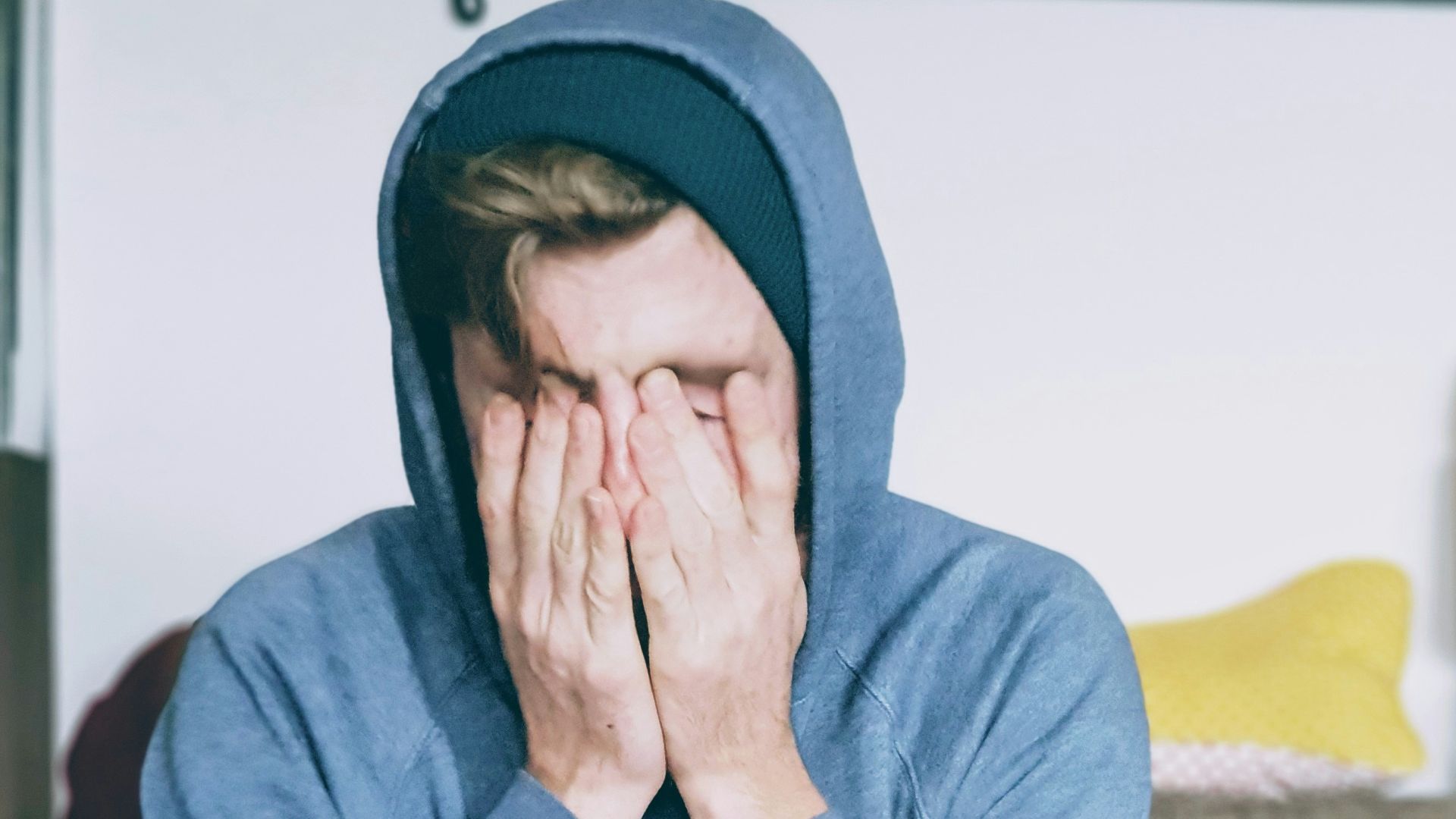man covering face with both hands while sitting on bench