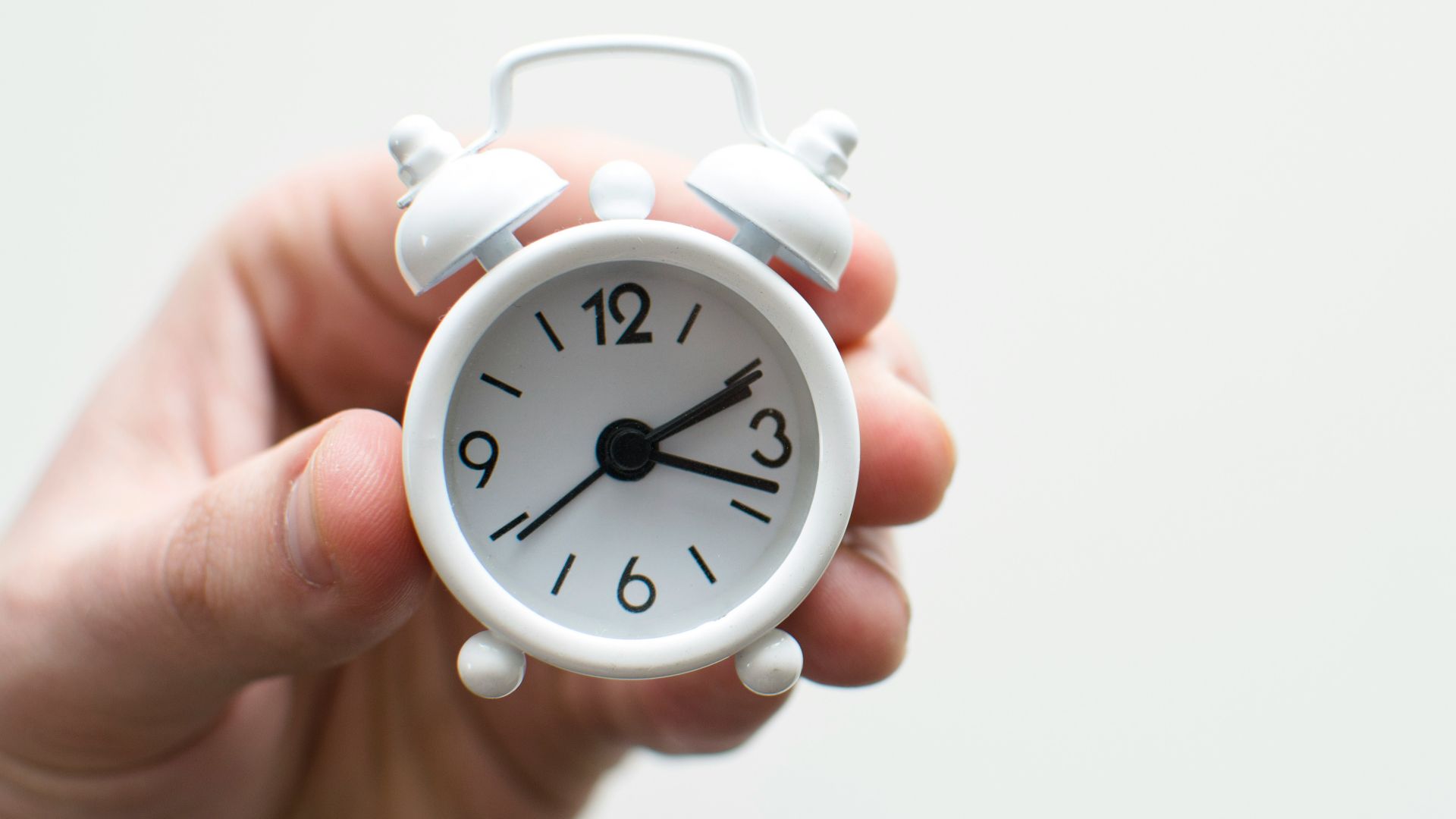 person holding white mini bell alarmclock