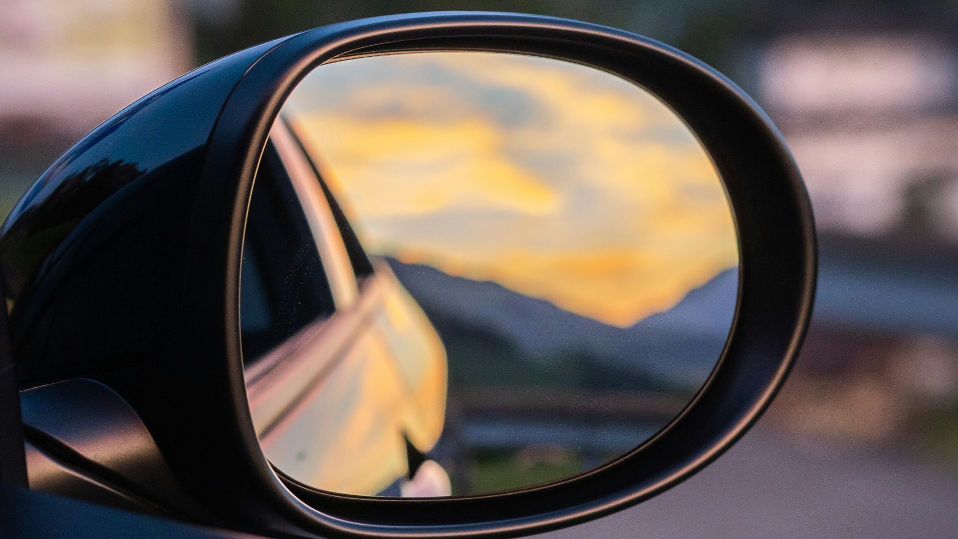 a side view mirror showing a yellow sunset